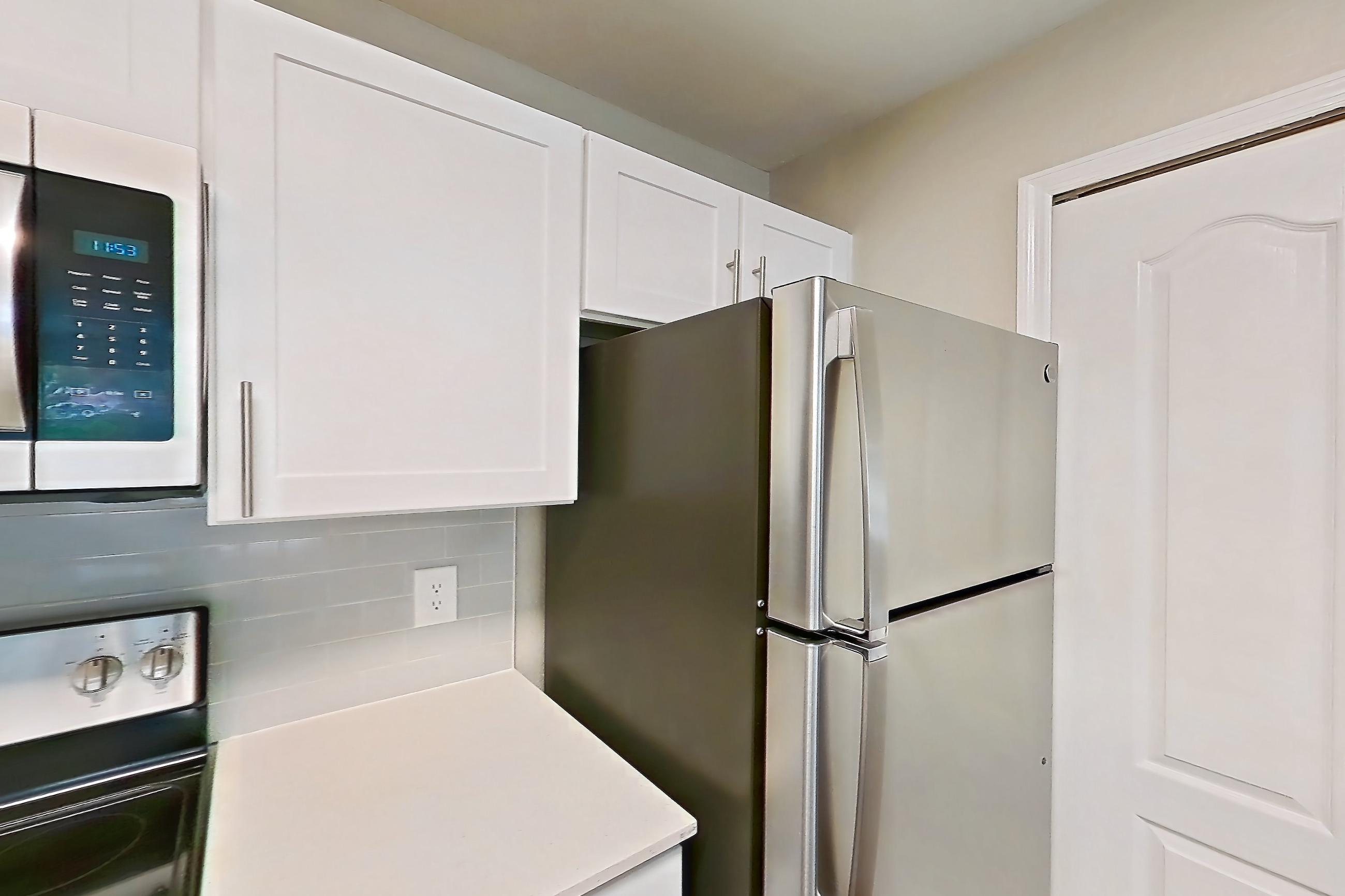 Kitchen with dishwasher, electric range, light countertops, light wood-finish flooring, microwave, oven/range, refrigerator, and stainless steel appliances, Apartment 15-105 at Boot Ranch