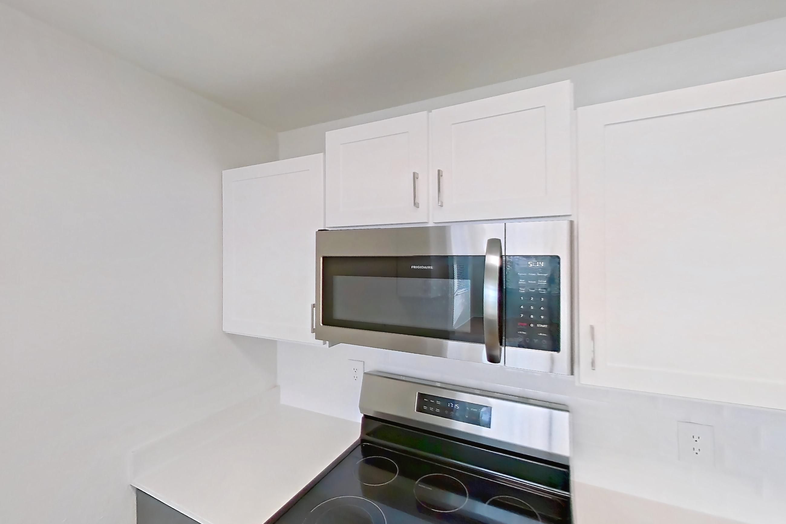 Kitchen with dishwasher, electric range, light countertops, light wood-finish flooring, microwave, oven/range, refrigerator, and stainless steel appliances, Apartment 15-308 at Boot Ranch