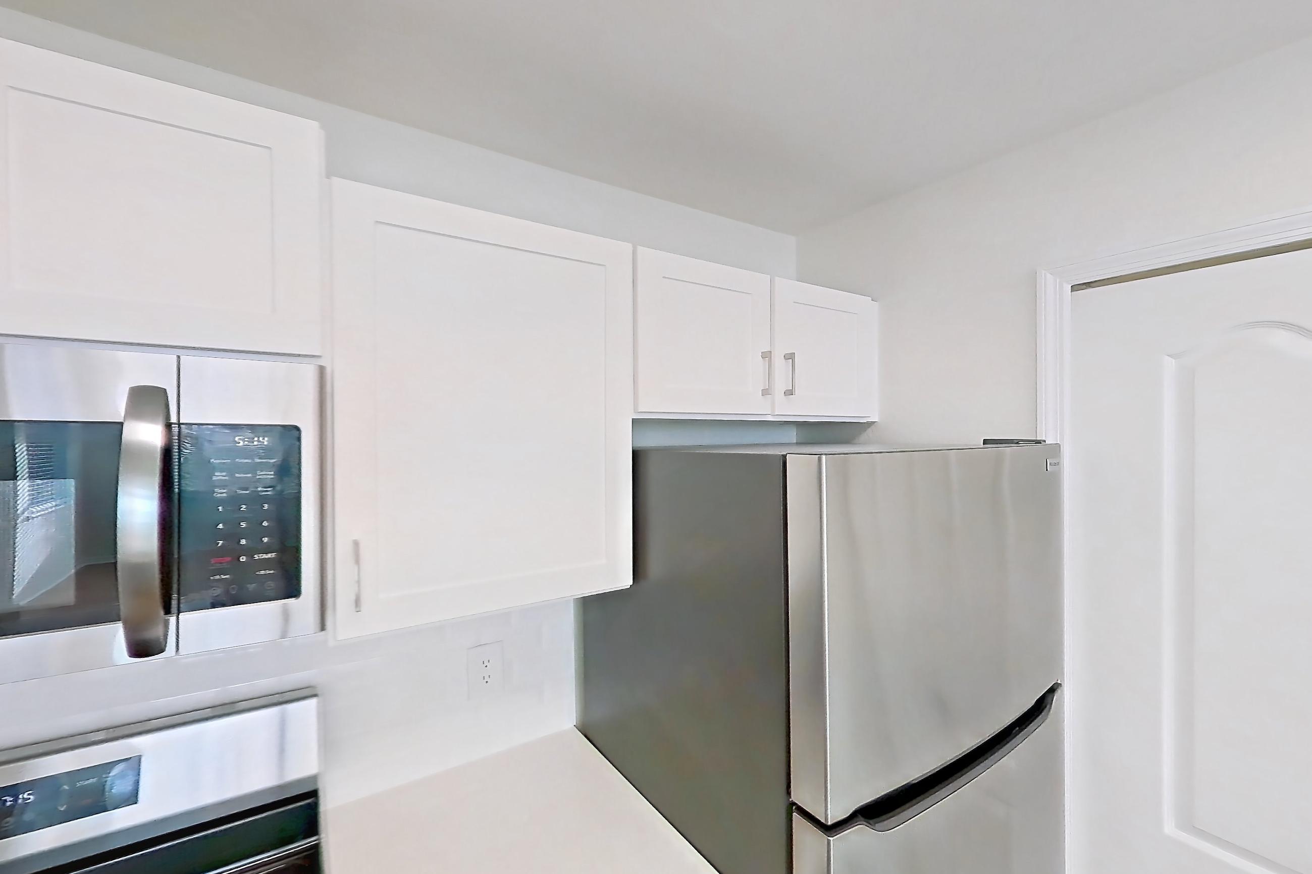 Kitchen with dishwasher, electric range, light countertops, light wood-finish flooring, microwave, oven/range, refrigerator, and stainless steel appliances, Apartment 15-308 at Boot Ranch