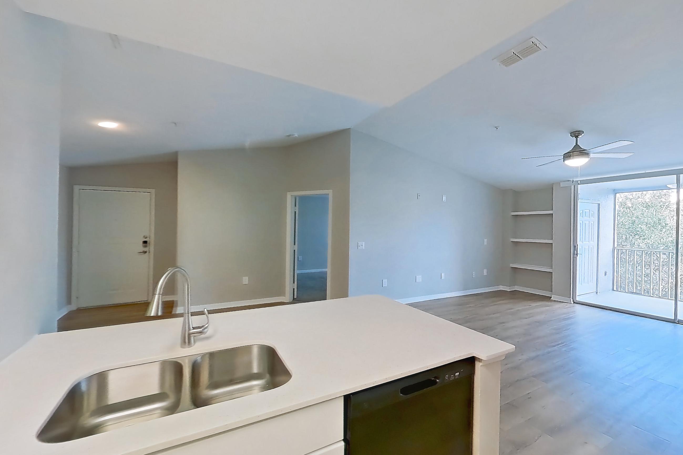 Kitchen with black appliances, dishwasher, electric range, light countertops, light stone countertops, light wood-finish flooring, microwave, oven/range, refrigerator, stainless steel appliances, and white appliances, Apartment 16-301 at Boot Ranch