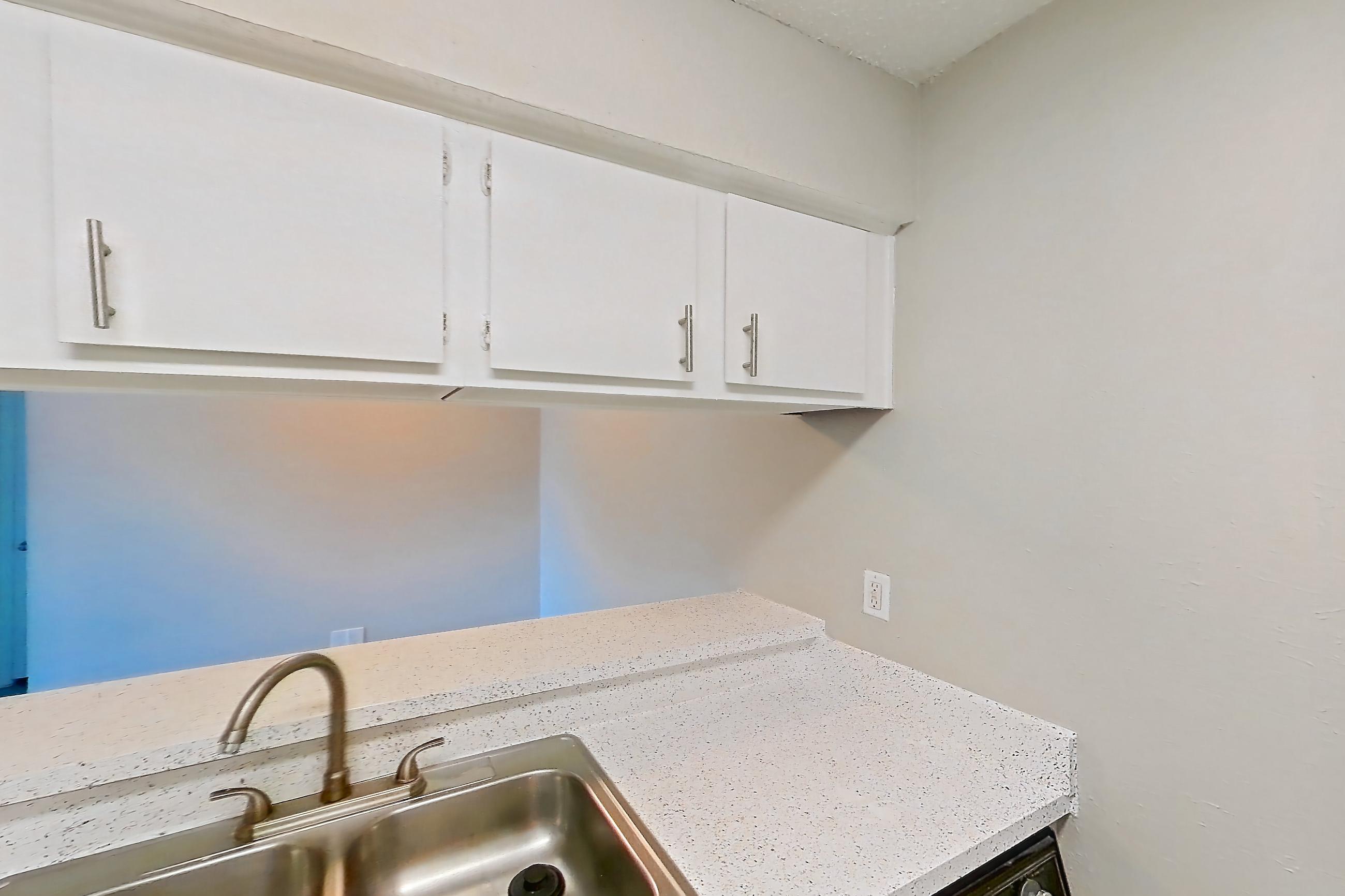 Kitchen with dark wood-finish flooring, dishwasher, electric range, kitchen island, light countertops, light stone countertops, light wood-finish flooring, oven/range, and white appliances, Apartment 1008 at Westgate