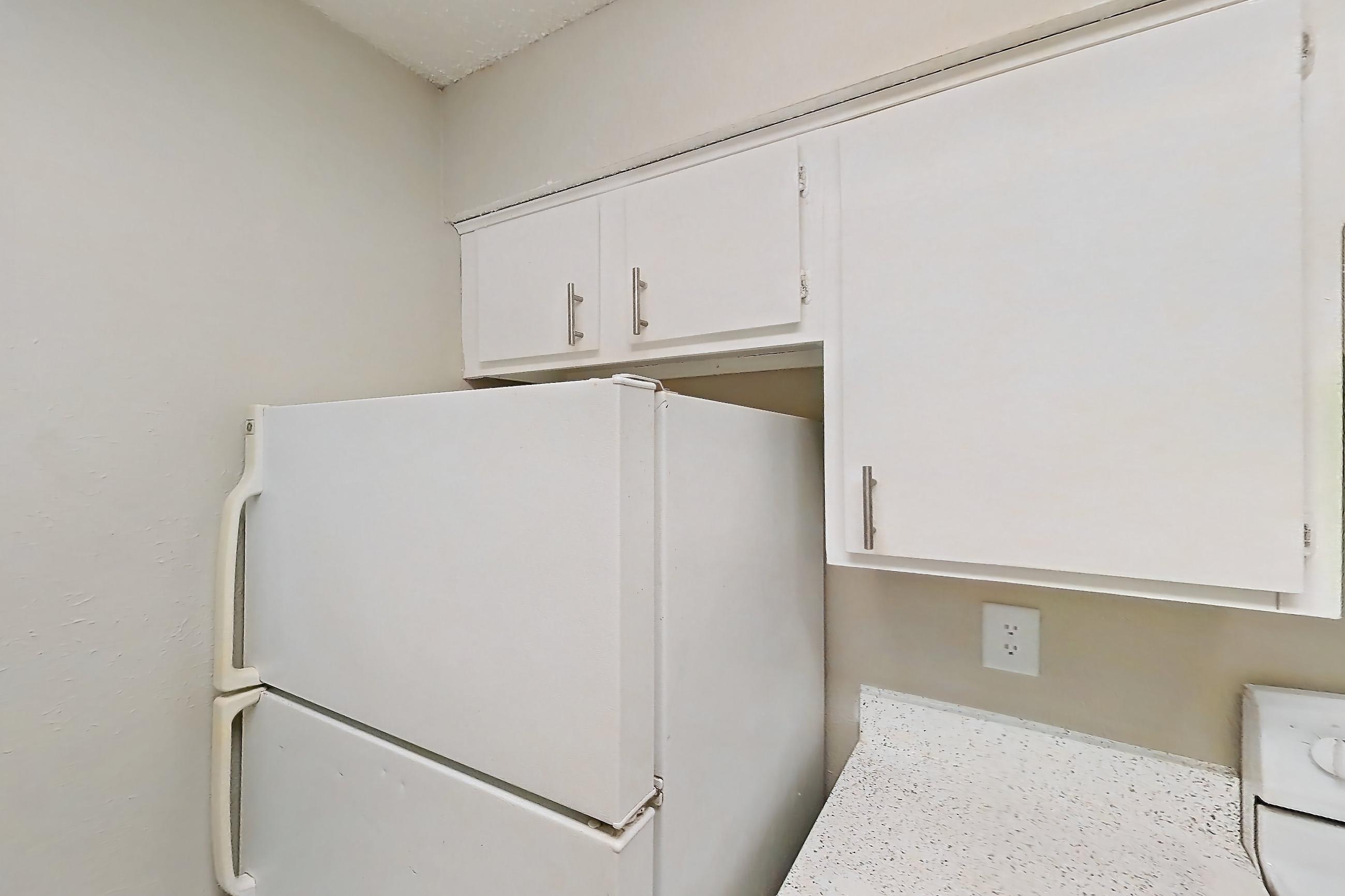 Kitchen with dark wood-finish flooring, dishwasher, electric range, kitchen island, light countertops, light stone countertops, light wood-finish flooring, oven/range, and white appliances, Apartment 1008 at Westgate