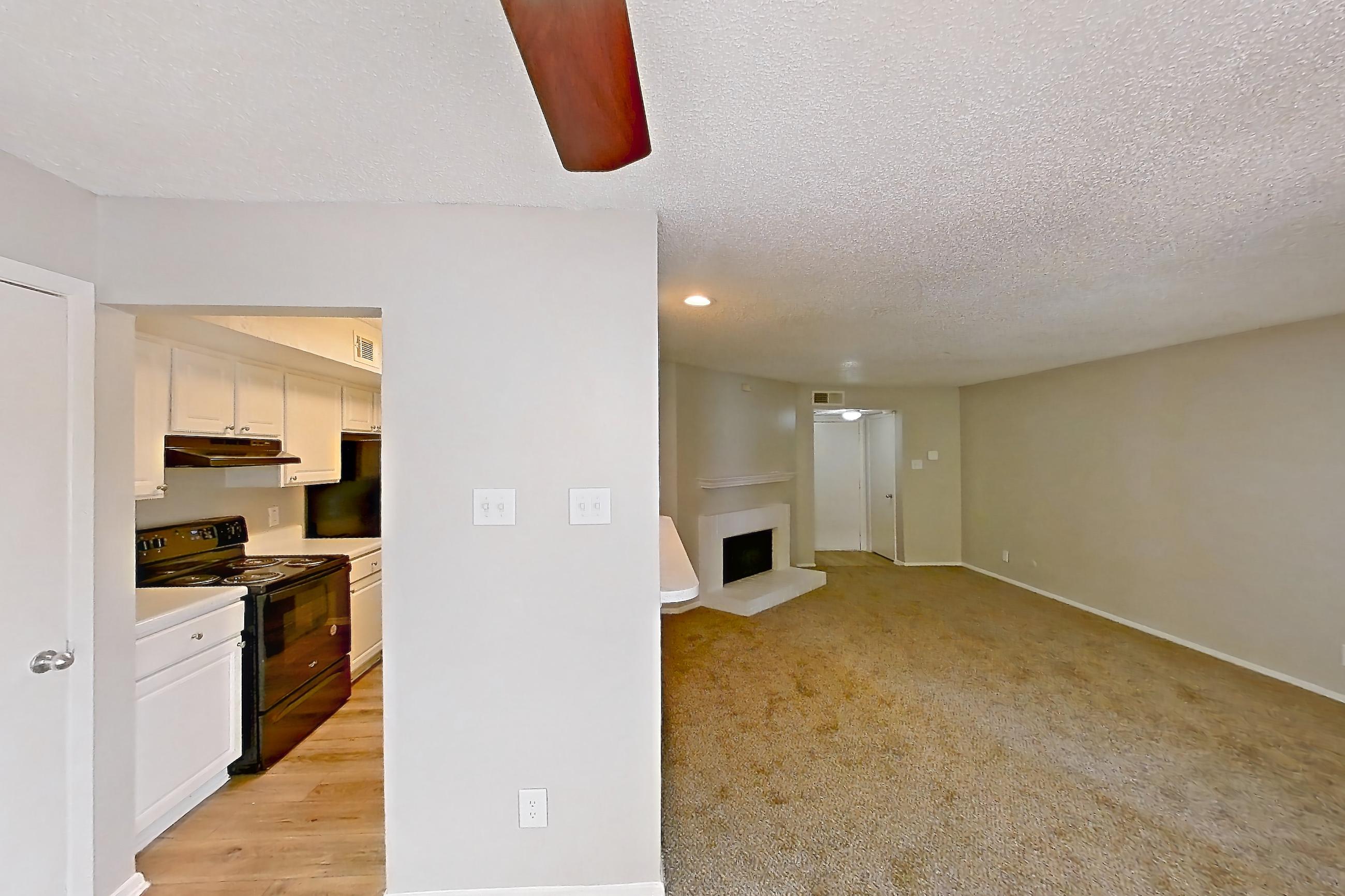 Dining room with black appliances, electric range, fireplace, light carpet, and oven/range, Apartment 0807 at Prestonwood Apartment Homes