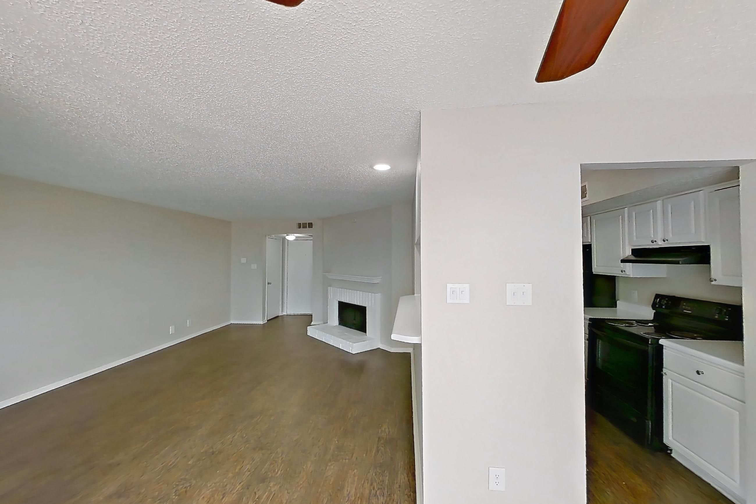 Dining room with black appliances, brick fireplace, dark wood-finish flooring, electric range, fireplace, and oven/range, Apartment 1506 at Prestonwood Apartment Homes