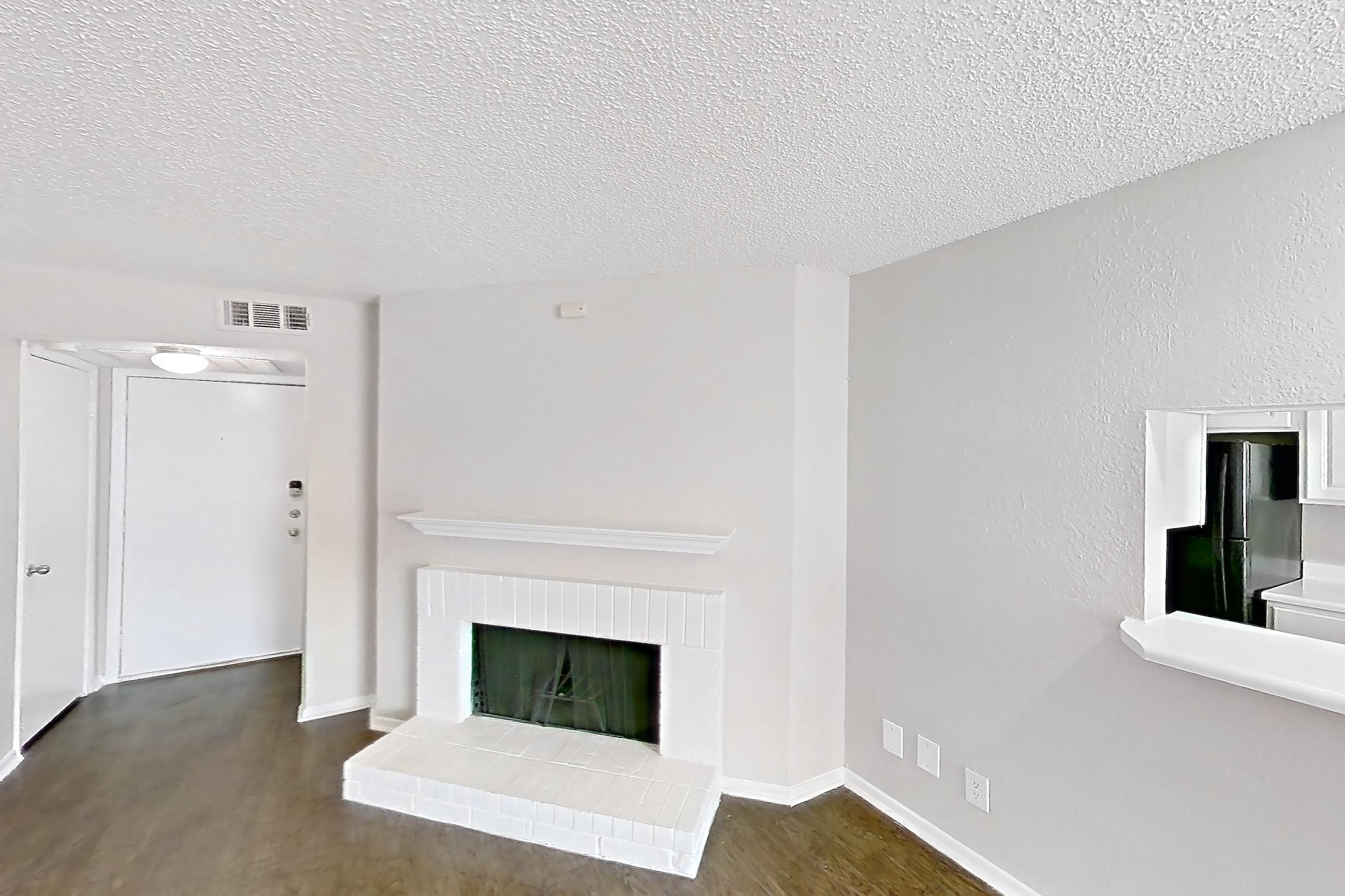 Living room with black appliances, brick fireplace, dark wood-finish flooring, electric range, fireplace, oven/range, and refrigerator, Apartment 1506 at Prestonwood Apartment Homes