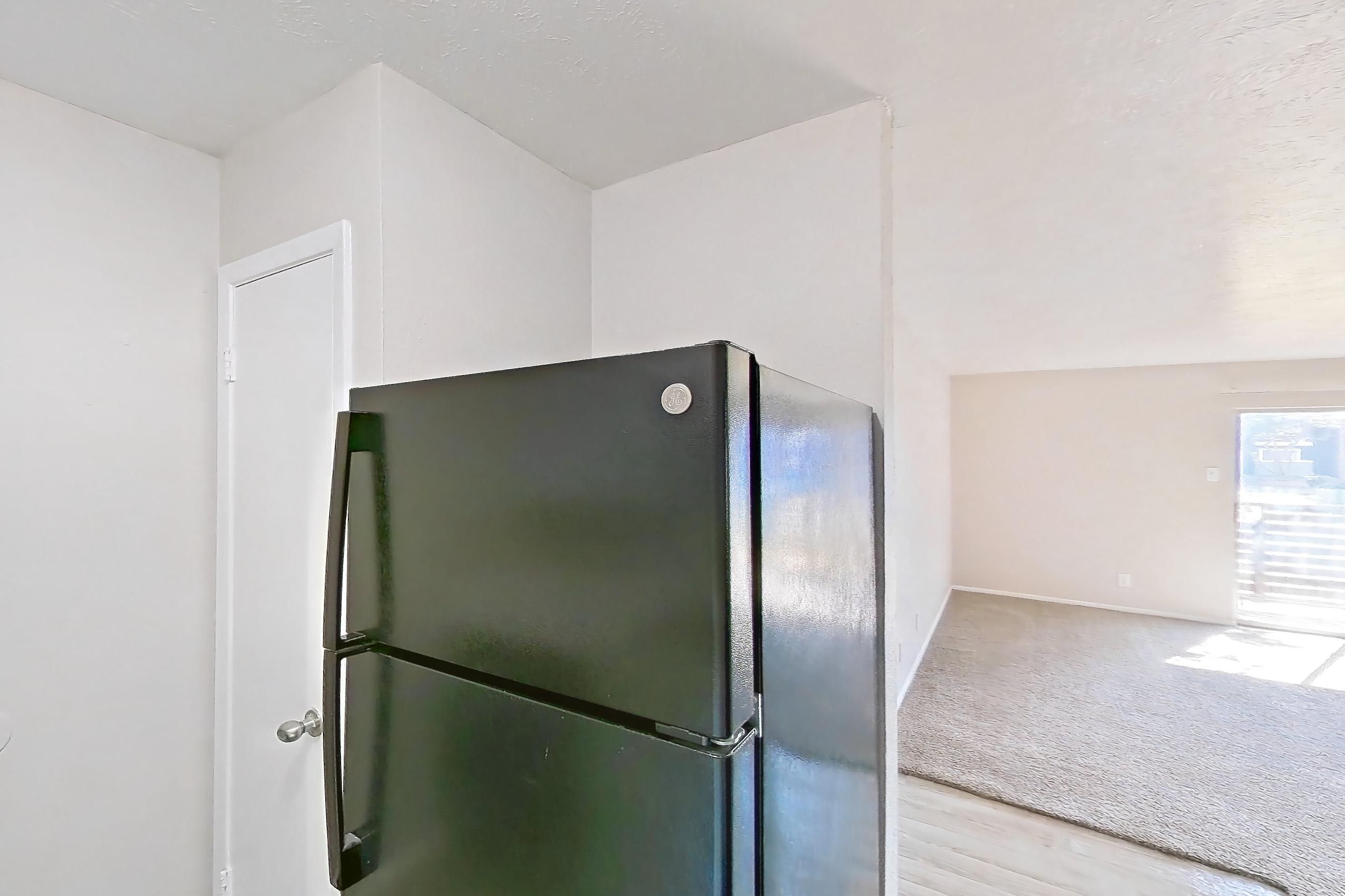 Kitchen with black appliances, electric range, light countertops, light stone countertops, light wood-finish flooring, oven/range, range hood, and refrigerator, Apartment 2328 at Westgate