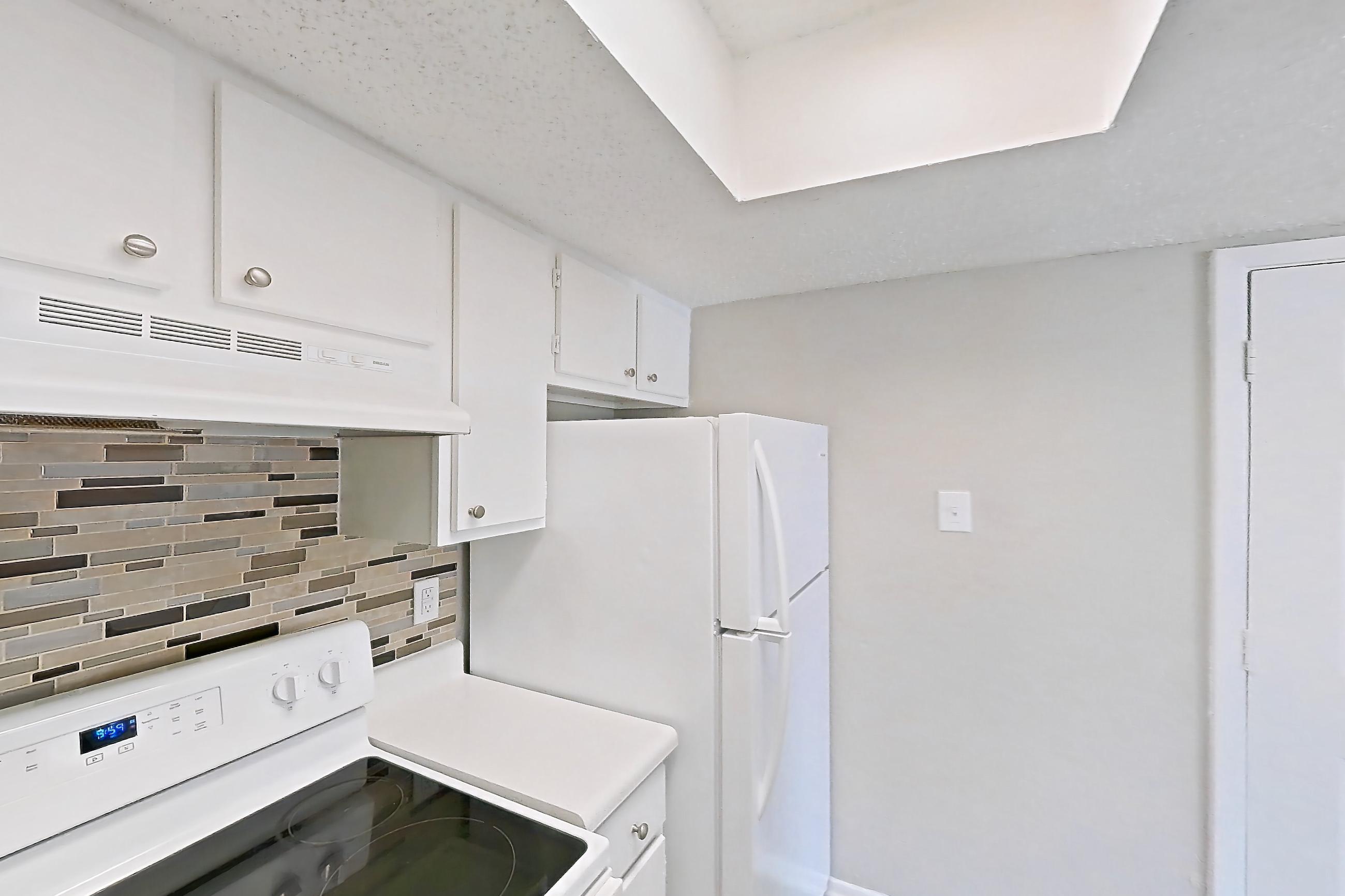 Kitchen with dark wood-finish flooring, electric range, light countertops, oven/range, refrigerator, white appliances, and wood-look tile flooring, Apartment 101 at Enclave at Prestonwood