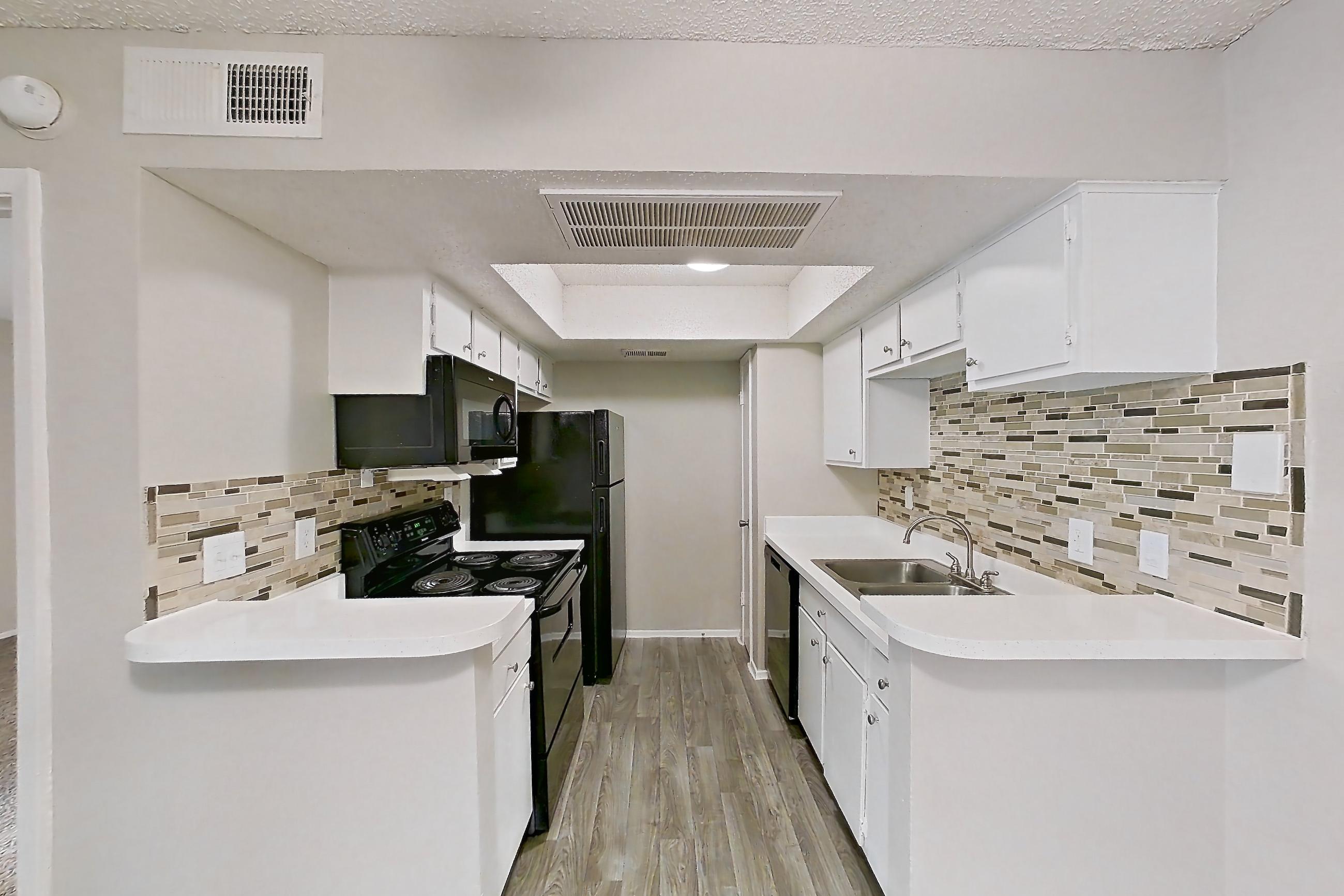 Dining room with black appliances, dishwasher, electric range, light carpet, light countertops, light wood-finish flooring, oven/range, refrigerator, and stainless steel appliances, Apartment 2013 at Enclave at Prestonwood