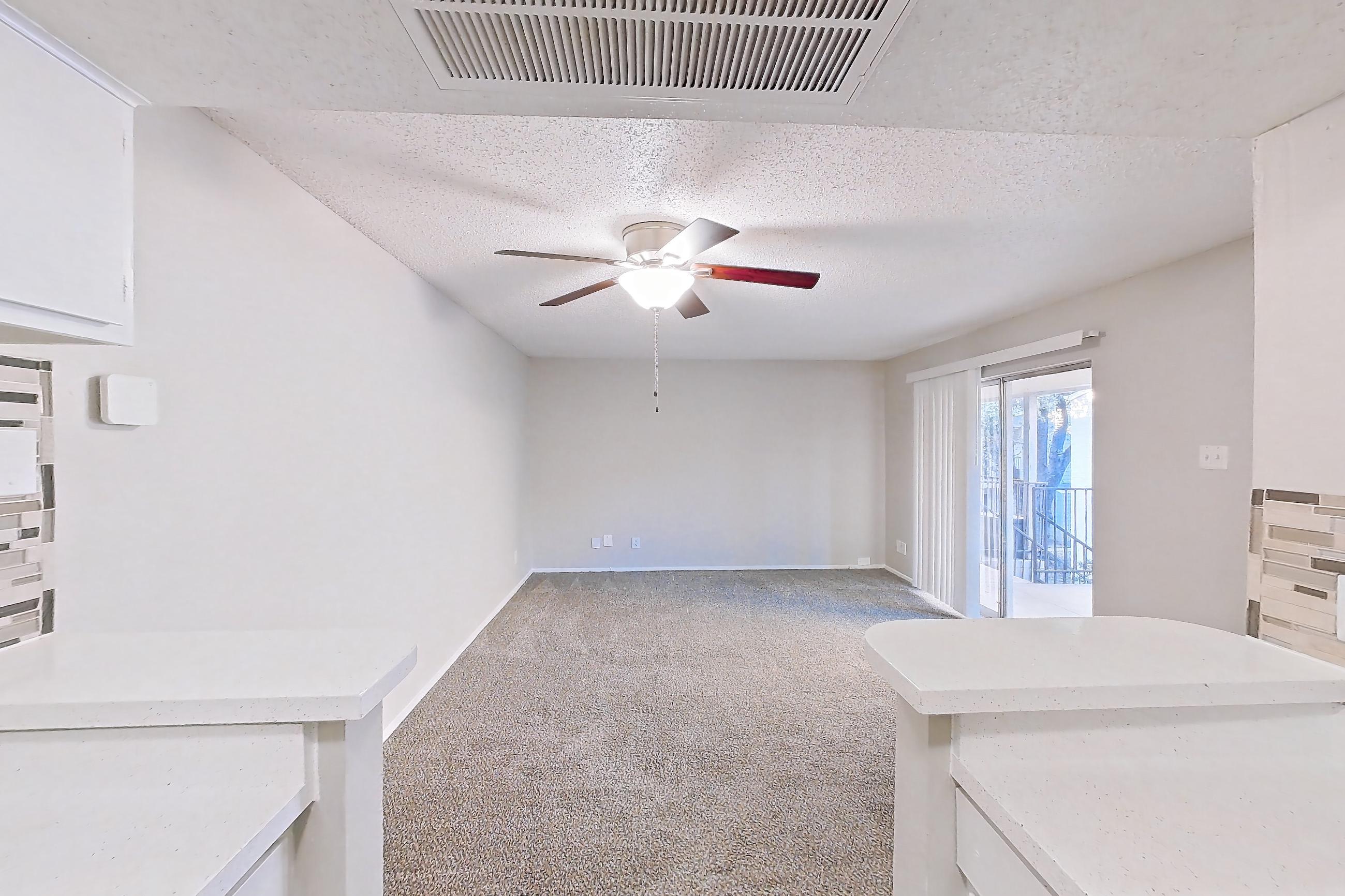 Kitchen with black appliances, dishwasher, electric range, light carpet, light countertops, light stone countertops, light wood-finish flooring, microwave, oven/range, and refrigerator, Apartment 2013 at Enclave at Prestonwood