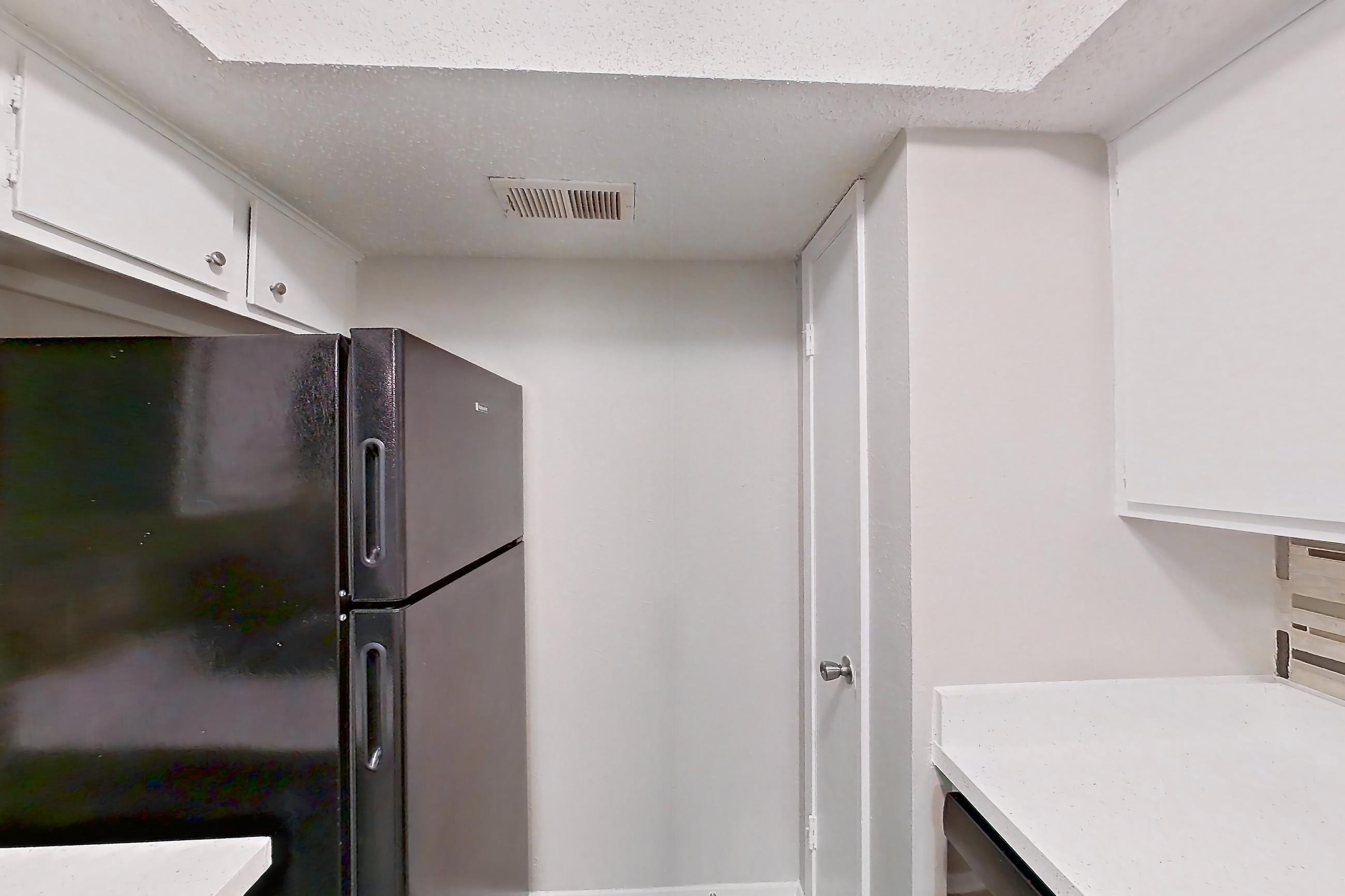 Kitchen with black appliances, dishwasher, electric range, light carpet, light countertops, light stone countertops, light wood-finish flooring, microwave, oven/range, and refrigerator, Apartment 2013 at Enclave at Prestonwood