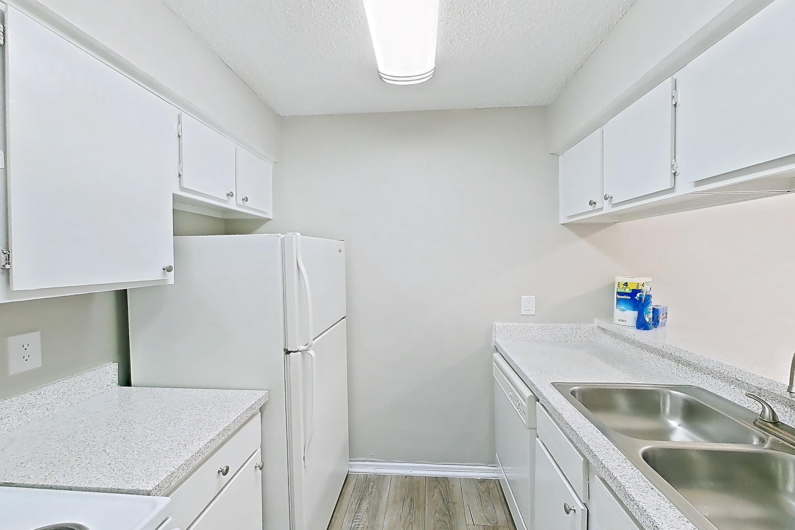 Kitchen with dishwasher, electric range, light countertops, light stone countertops, light wood-finish flooring, oven/range, refrigerator, and white appliances, Apartment 404 at Westgate