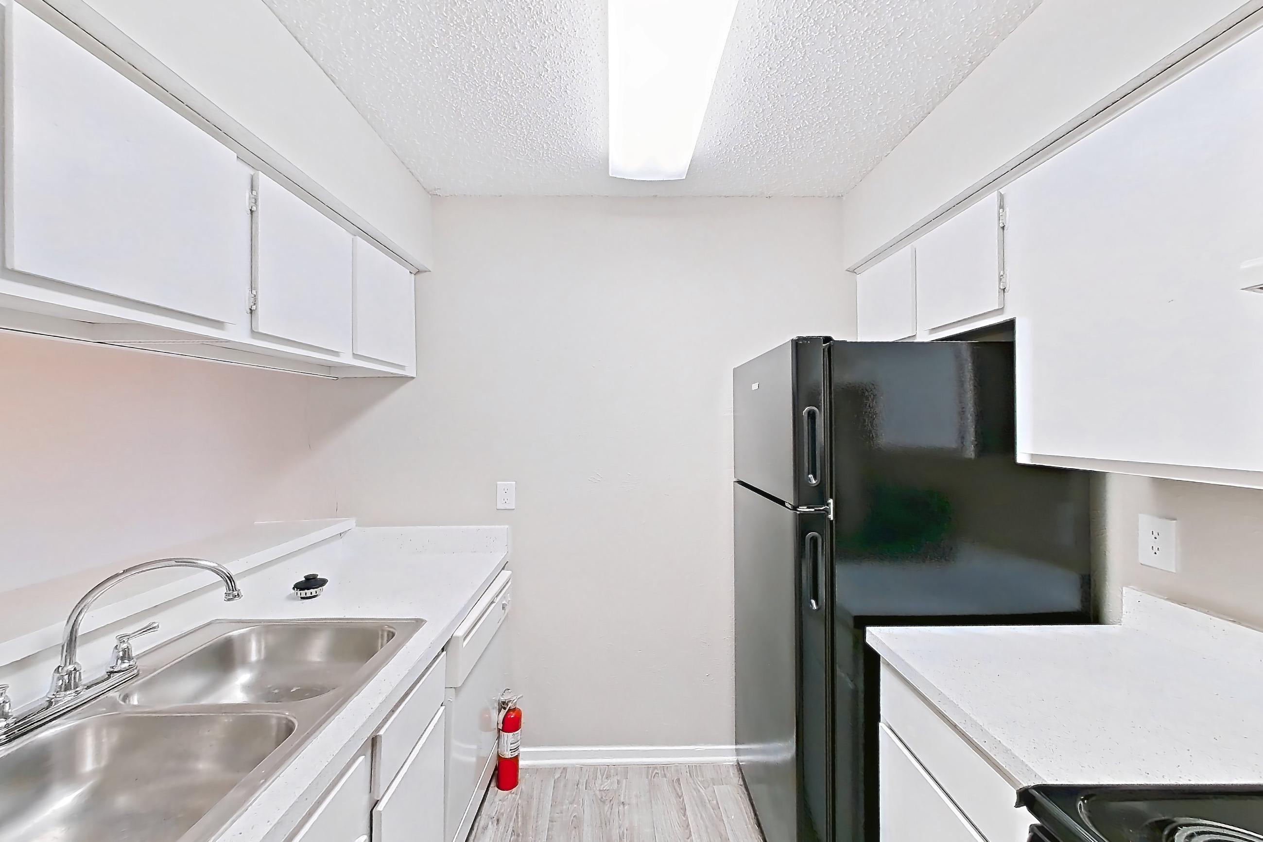 Kitchen with black appliances, electric range, light countertops, light stone countertops, light wood-finish flooring, oven/range, and refrigerator, Apartment 601 at Westgate
