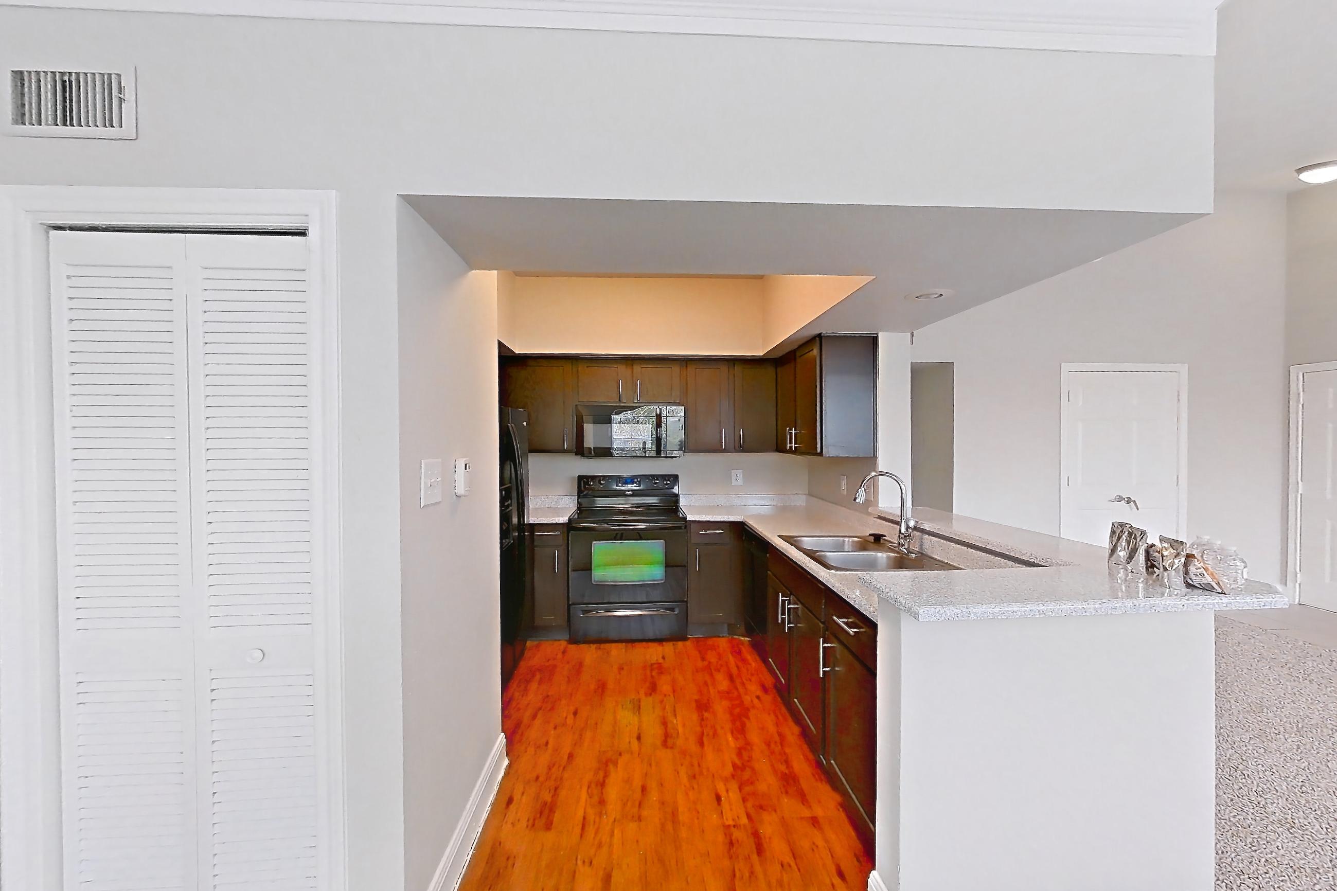 Dining room with black appliances, electric range, light carpet, light stone countertops, light wood-finish flooring, oven/range, and refrigerator, Unit 0216 at Champions Park