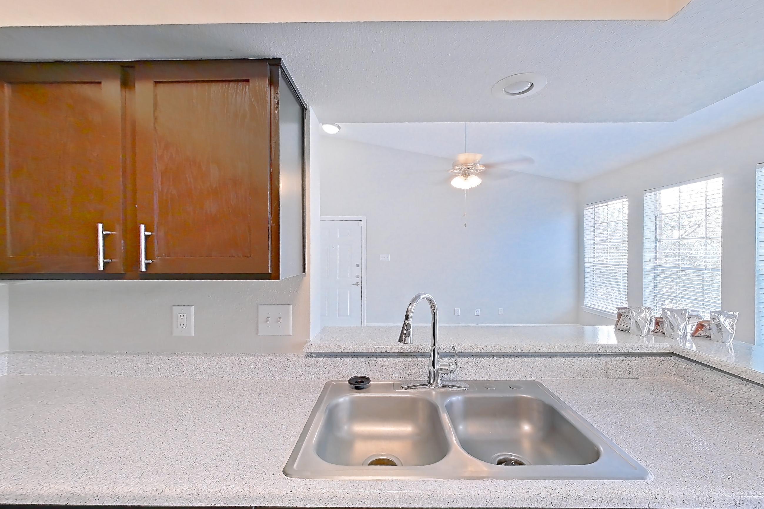 Kitchen with black appliances, dishwasher, electric range, light carpet, light countertops, light stone countertops, light wood-finish flooring, oven/range, refrigerator, and stainless steel appliances, Unit 0216 at Champions Park