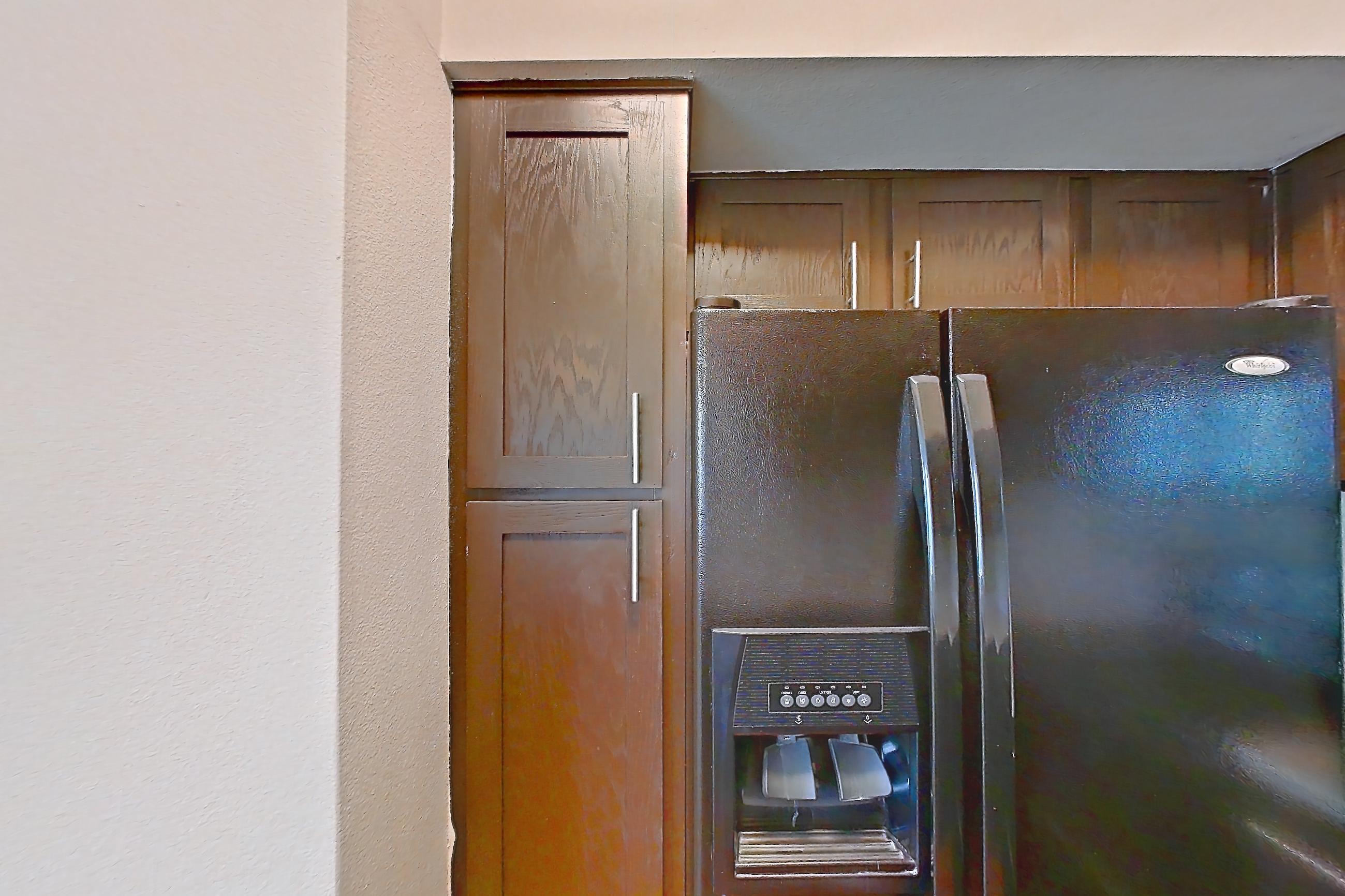 Kitchen with black appliances, dishwasher, electric range, light carpet, light countertops, light stone countertops, light wood-finish flooring, oven/range, refrigerator, and stainless steel appliances, Unit 0216 at Champions Park