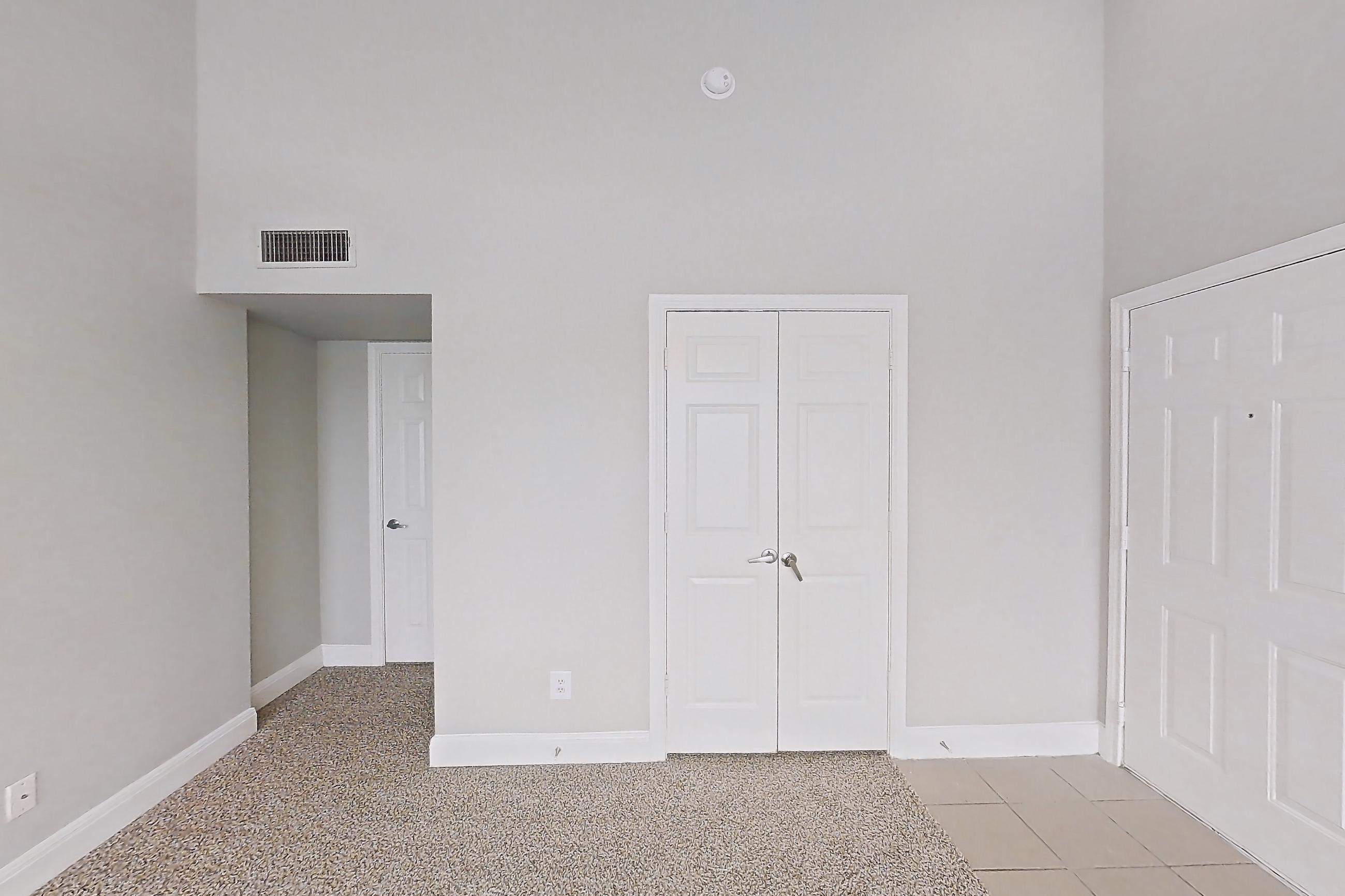 Living room with black appliances, light carpet, light stone countertops, and refrigerator, Unit 0216 at Champions Park