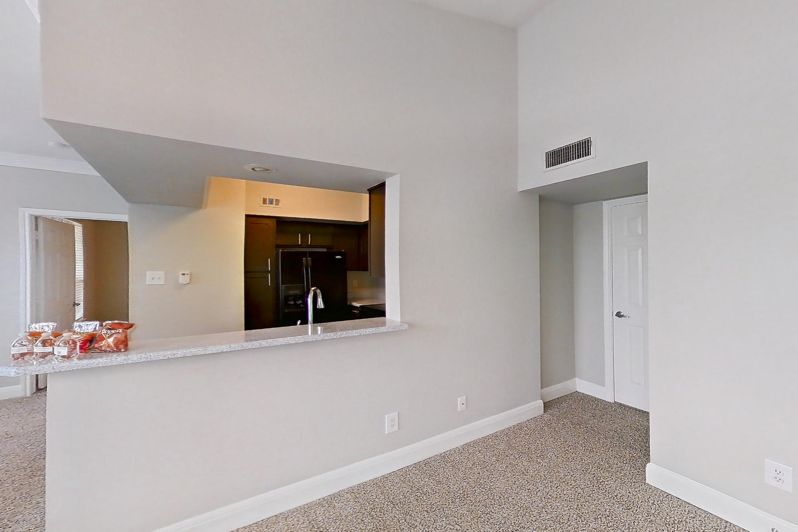 Living room with black appliances, light carpet, light stone countertops, and refrigerator, Unit 0216 at Champions Park