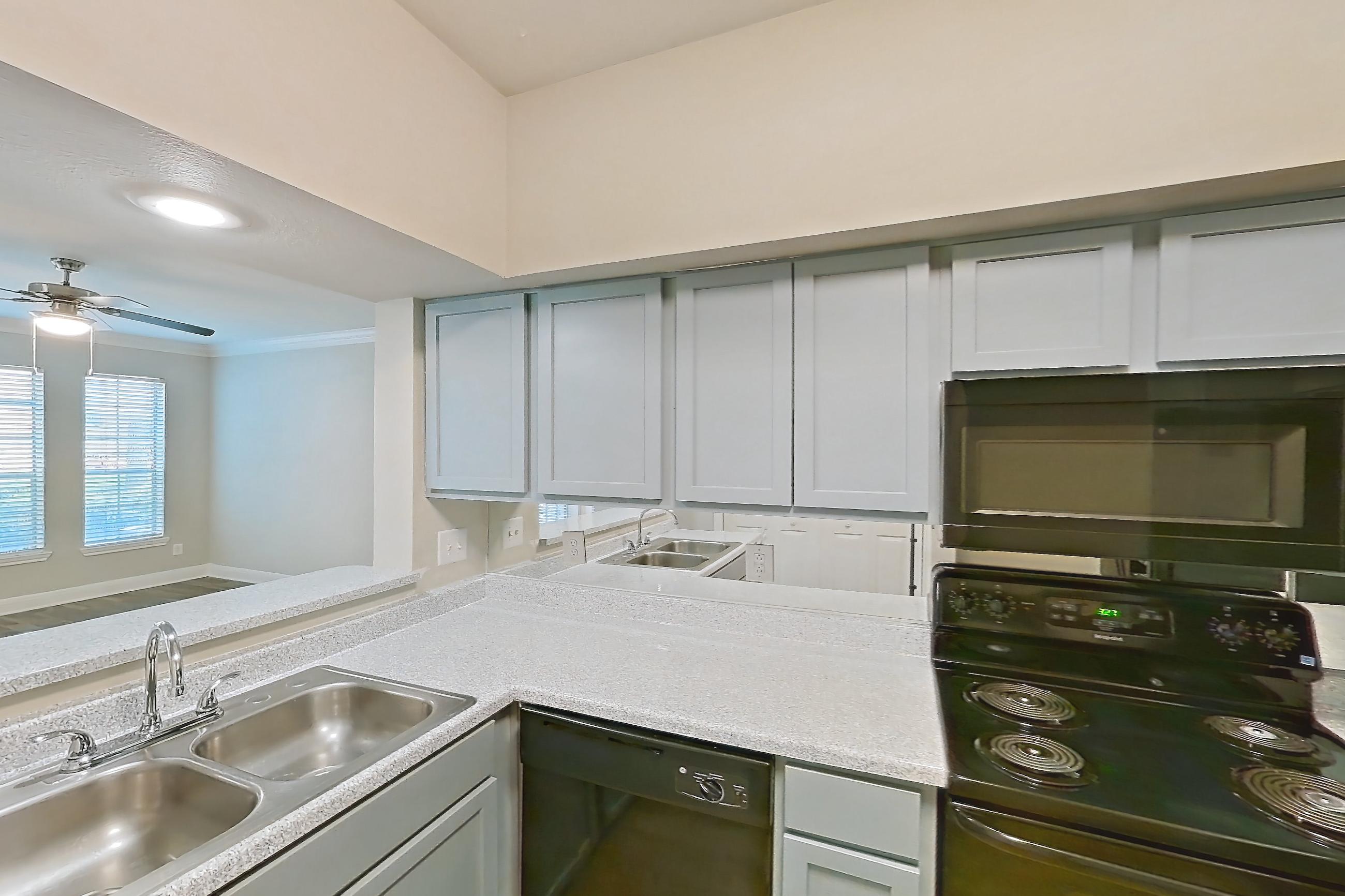 Kitchen space with black appliances, dishwasher, electric range, light countertops, light wood-finish flooring, microwave, oven/range, and wood-look tile flooring, Apartment 0301 at Champions Park