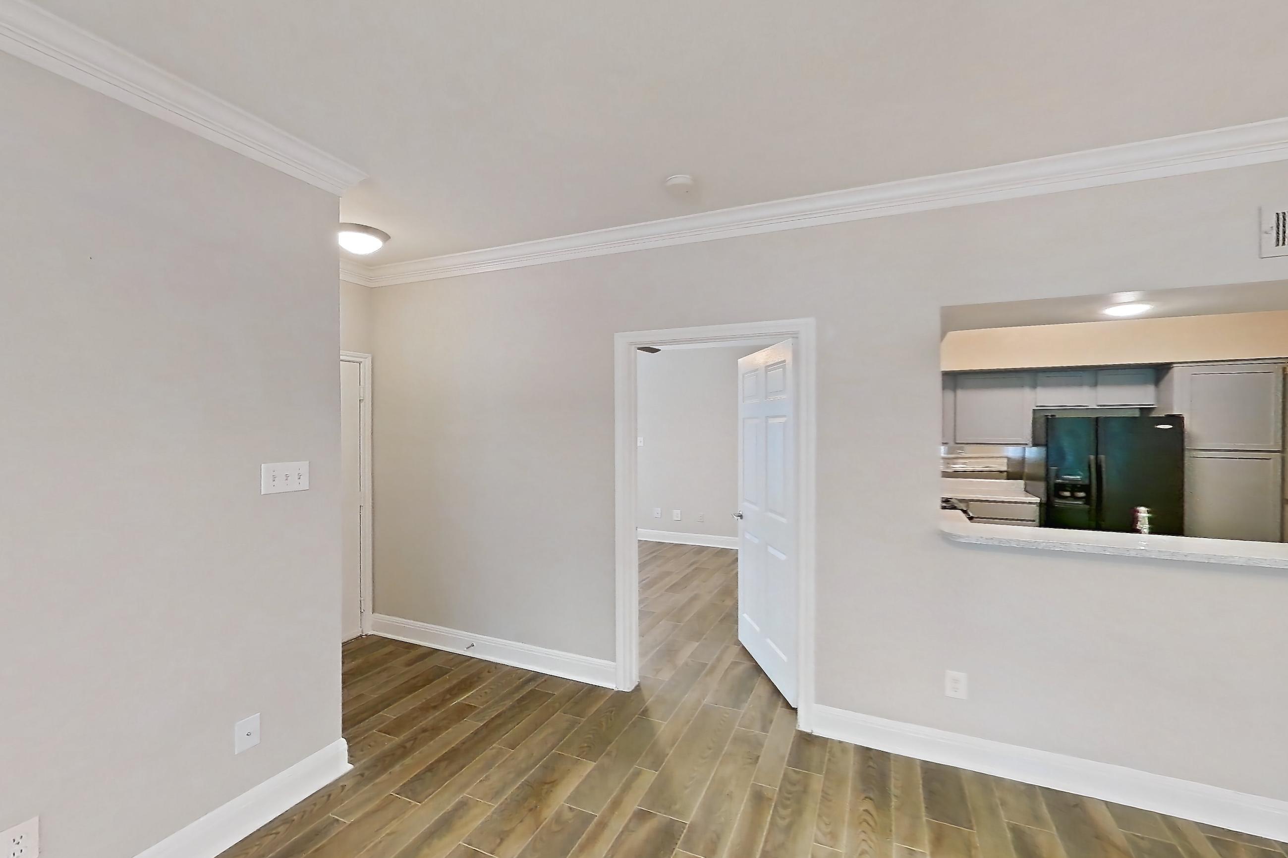 Living room with black appliances, light wood-finish flooring, refrigerator, water & ice dispenser, and wood-look tile flooring, Apartment 0301 at Champions Park