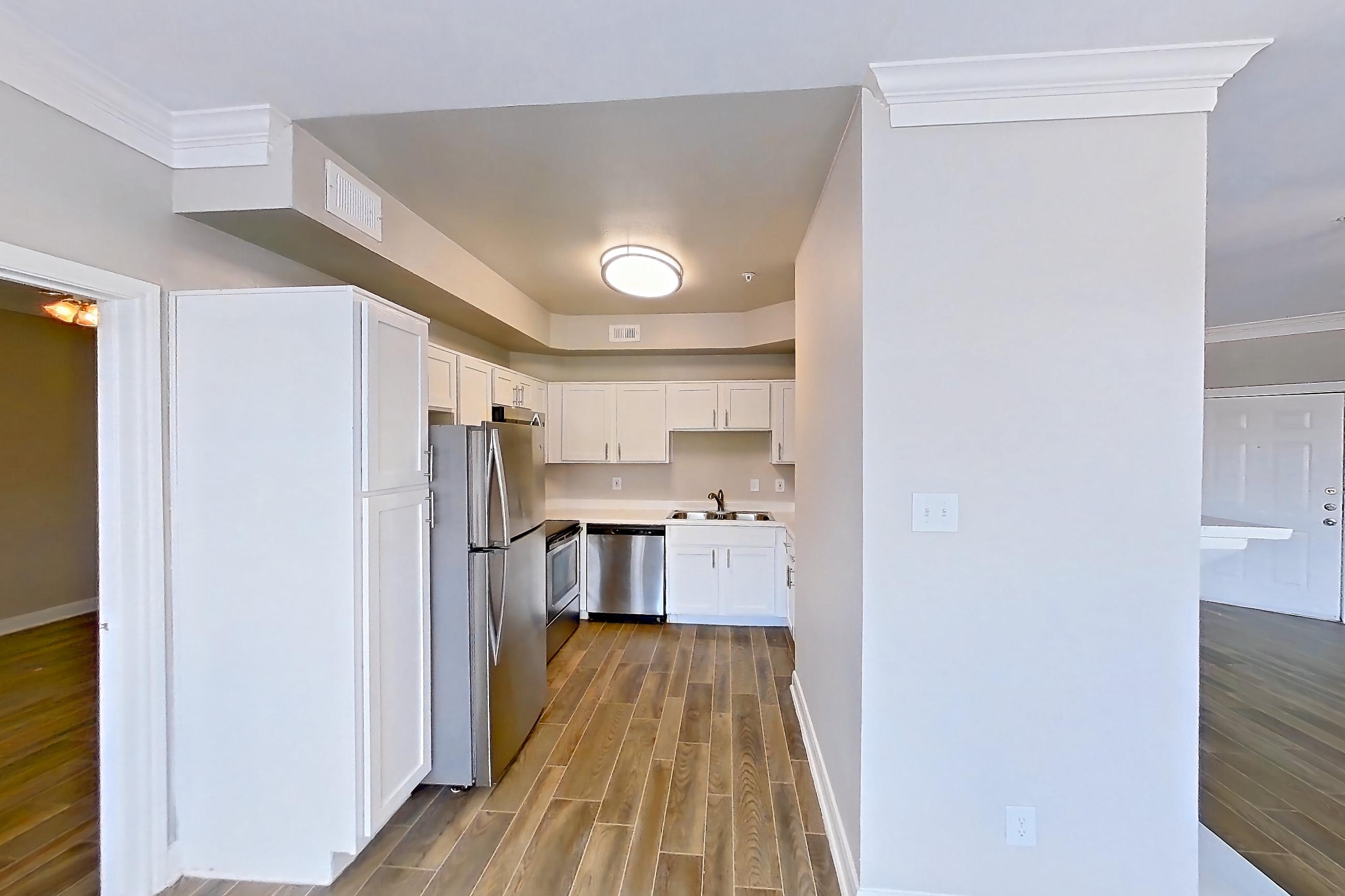 Dining room with dark wood-finish flooring, dishwasher, electric range, light countertops, oven/range, refrigerator, stainless steel appliances, and wood-look tile flooring, Apartment 609 at Champions Centre