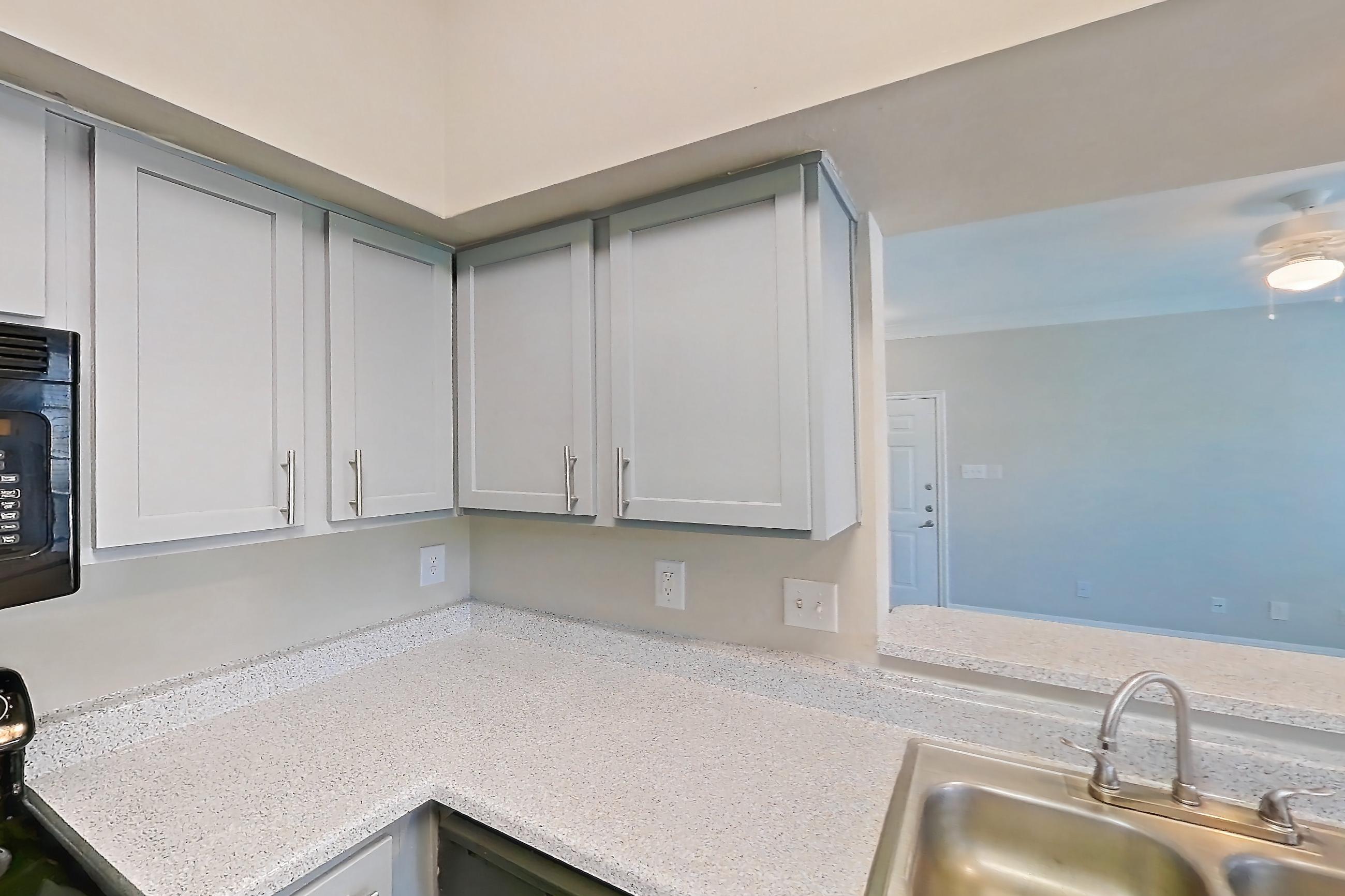 Kitchen with black appliances, dishwasher, light countertops, light stone countertops, light wood-finish flooring, oven/range, refrigerator, water & ice dispenser, and wood-look tile flooring, Apartment 0308 at Champions Park