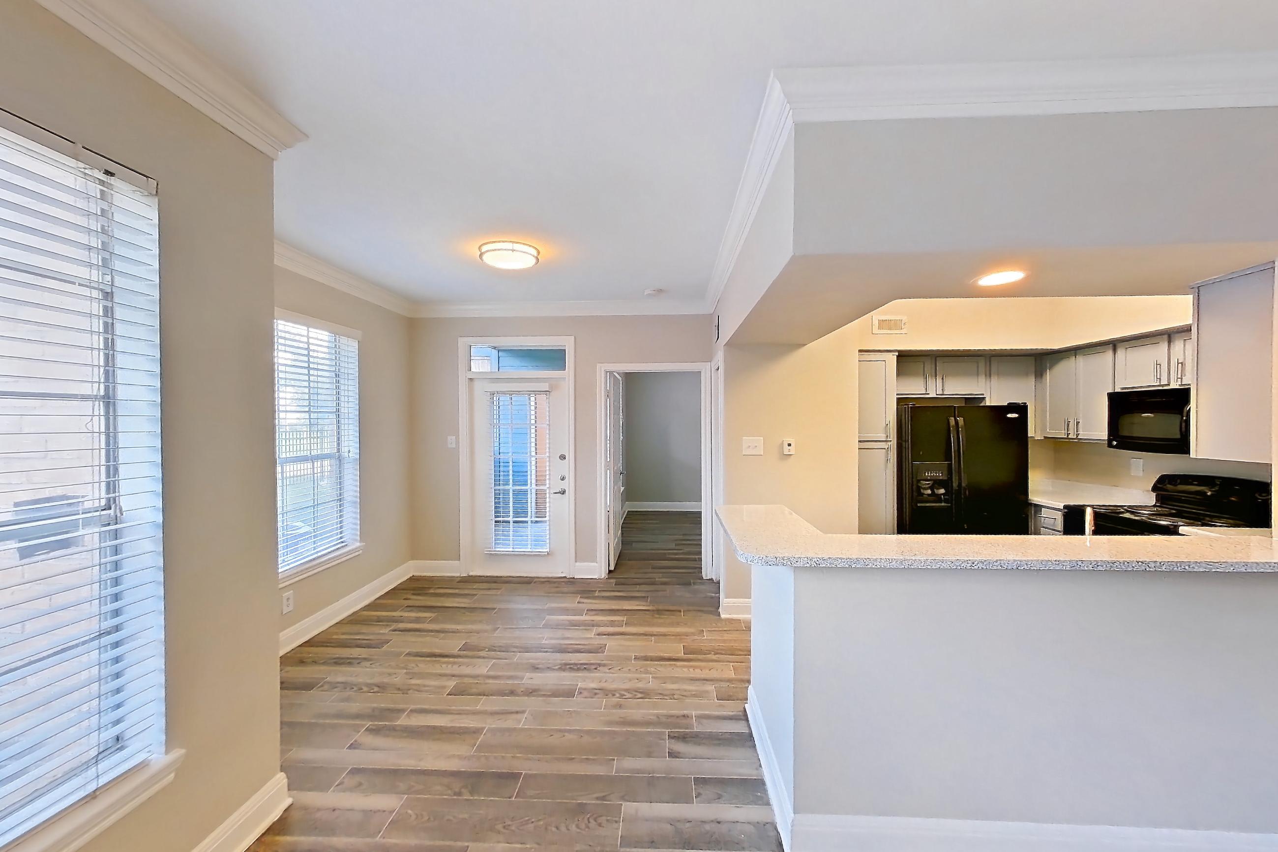 Living room with black appliances, dark wood-finish flooring, refrigerator, water & ice dispenser, and wood-look tile flooring, Apartment 0308 at Champions Park