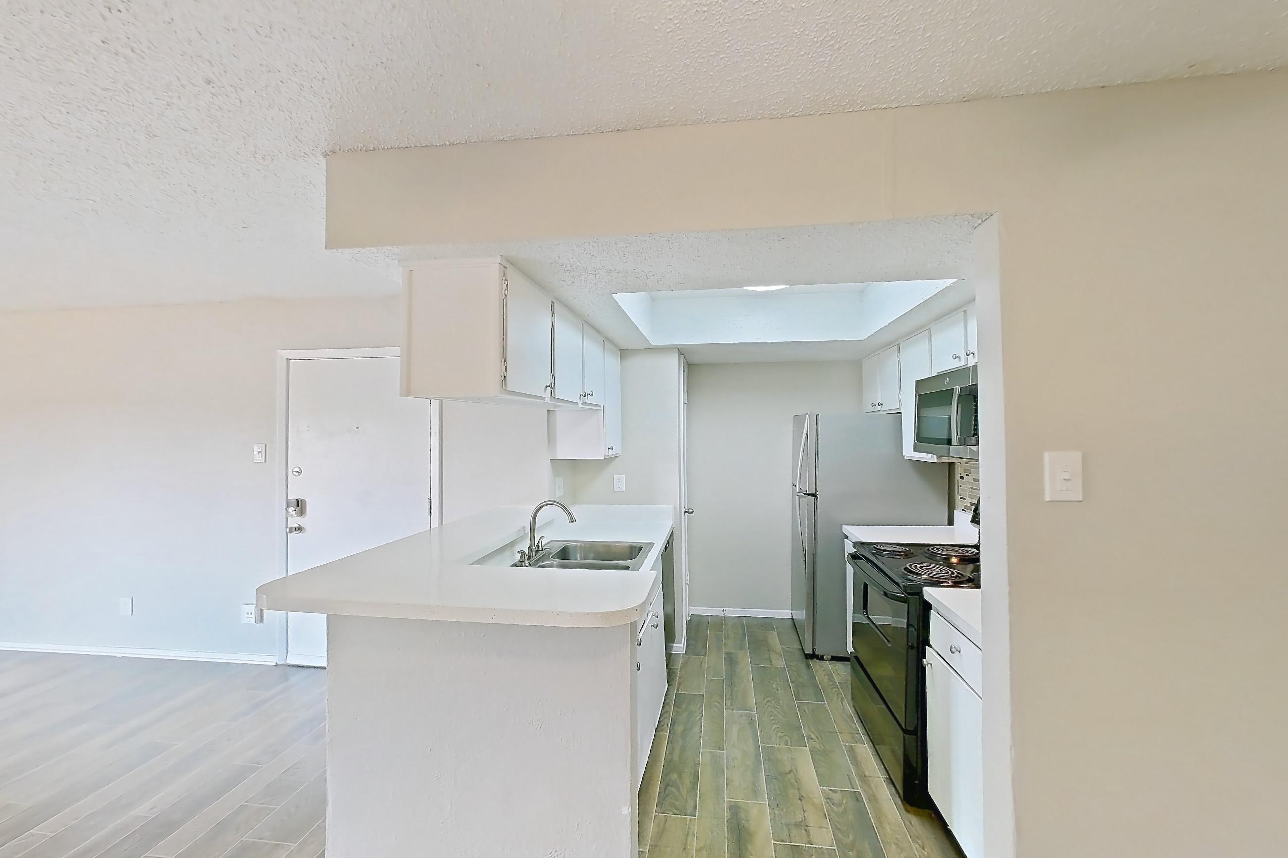 Dining room with fireplace, light countertops, light wood-finish flooring, refrigerator, white appliances, and wood-look tile flooring, Apartment 1156 at Enclave at Prestonwood
