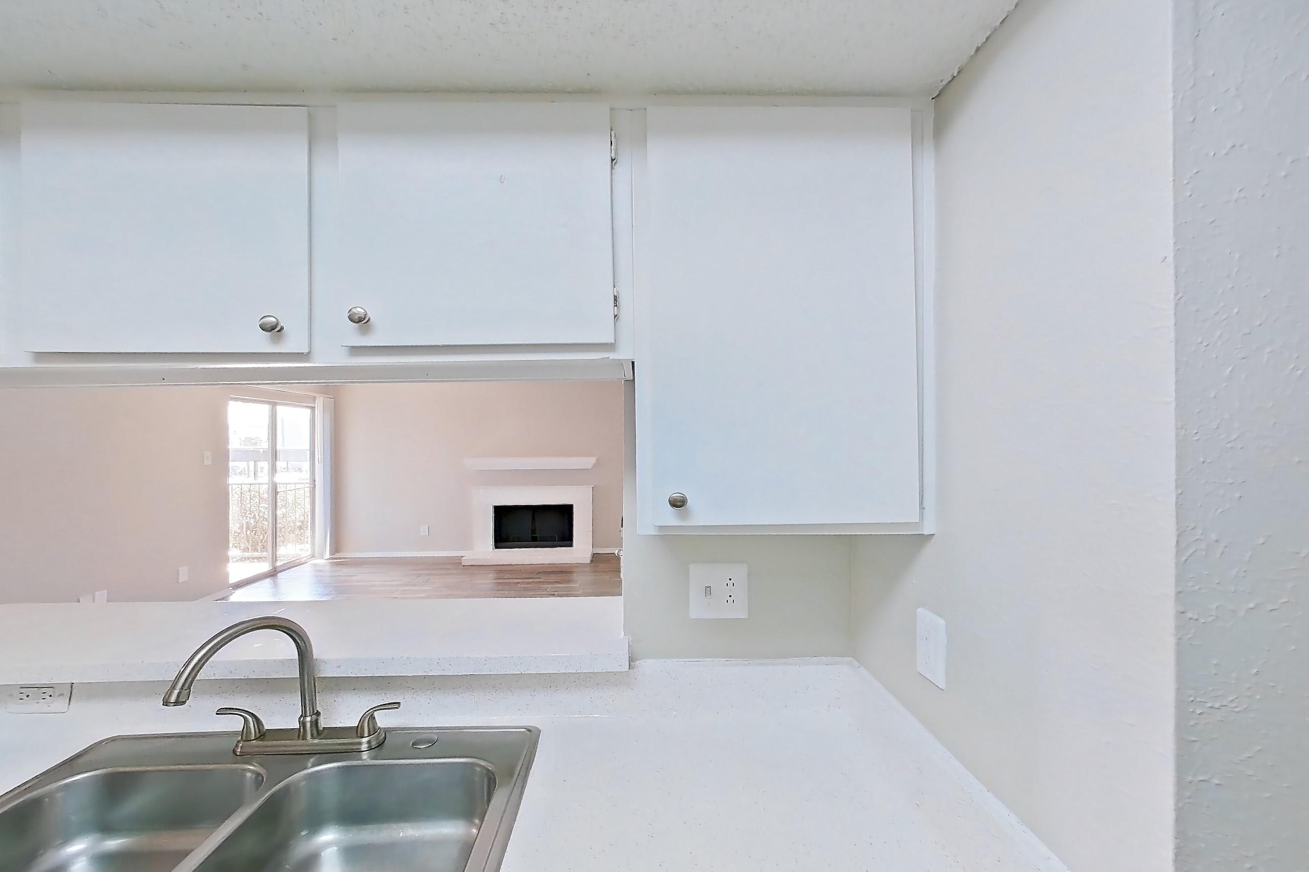 Kitchen with black appliances, dishwasher, electric range, fireplace, light countertops, light wood-finish flooring, oven/range, refrigerator, stainless steel appliances, and wood-look tile flooring, Apartment 1156 at Enclave at Prestonwood