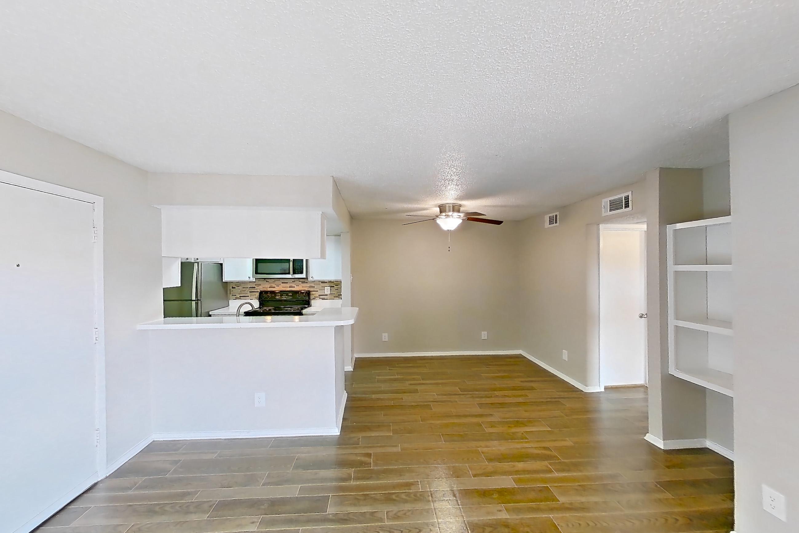 Living room with black appliances, dark wood-finish flooring, oven/range, refrigerator, stainless steel appliances, and wood-look tile flooring, Apartment 1156 at Enclave at Prestonwood