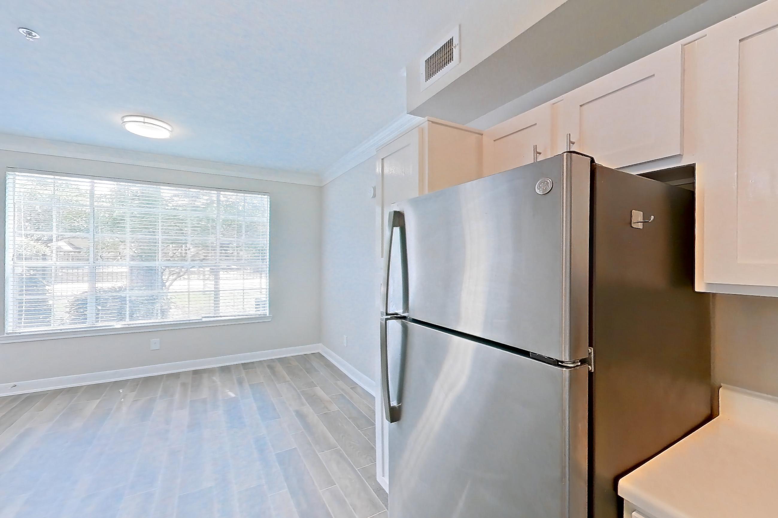Kitchen with dark wood-finish flooring, dishwasher, electric range, light countertops, light wood-finish flooring, oven/range, refrigerator, stainless steel appliances, and wood-look tile flooring, Apartment 805 at Champions Centre