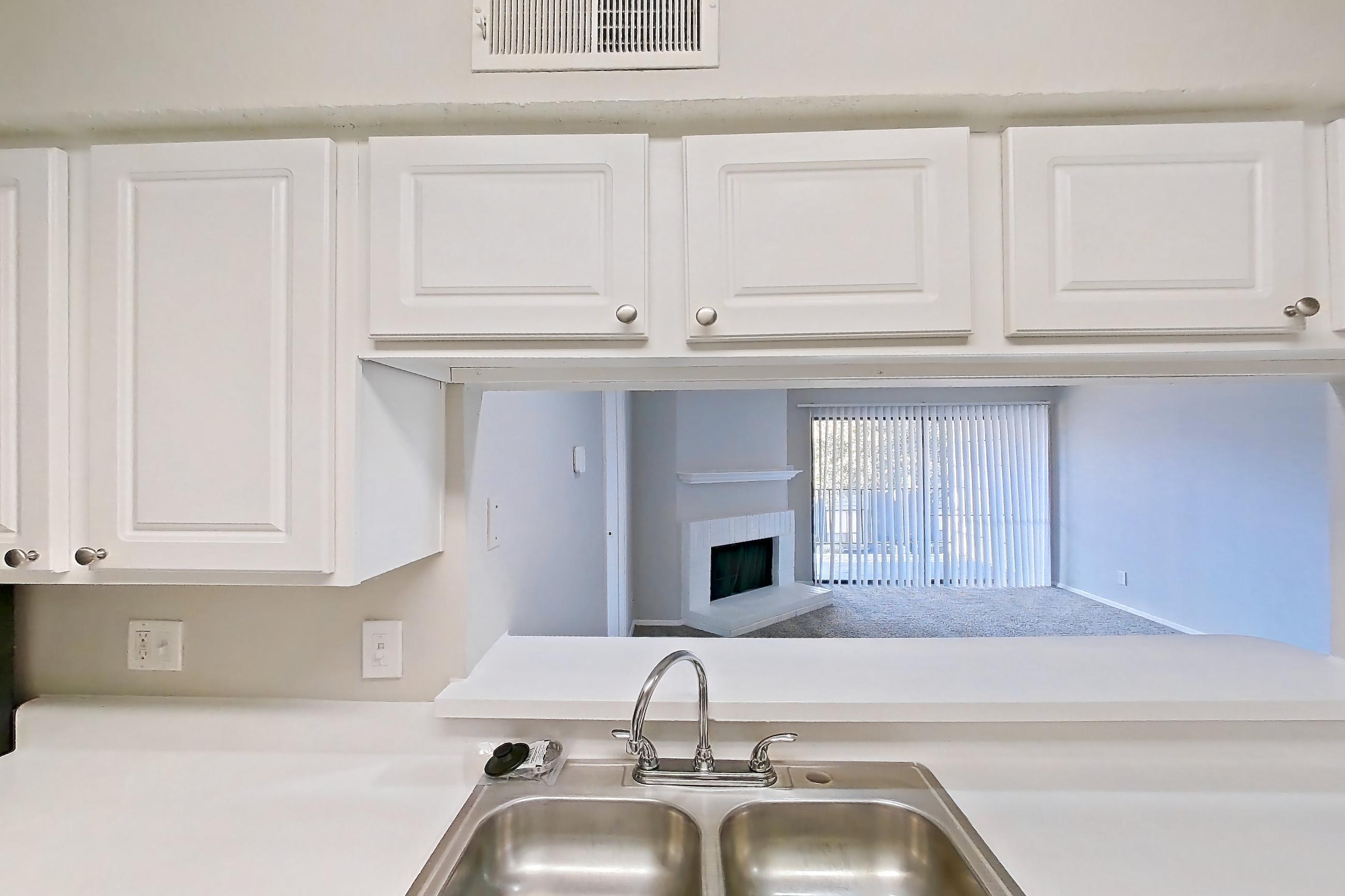 Kitchen with black appliances, brick fireplace, dishwasher, electric range, fireplace, light countertops, light wood-finish flooring, oven/range, and refrigerator, Apartment 0309 at Prestonwood Apartment Homes