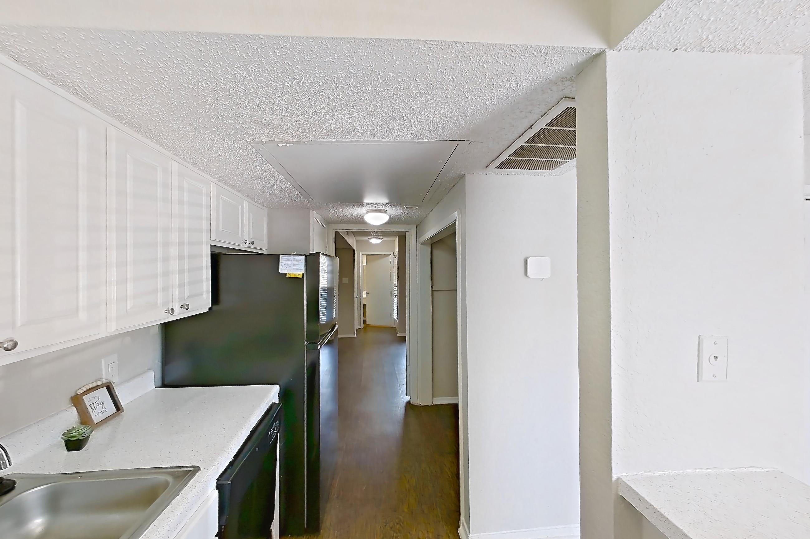 Kitchen with black appliances, dark wood-finish flooring, dishwasher, electric range, light countertops, oven/range, and refrigerator, Apartment 0105 at Prestonwood Apartment Homes