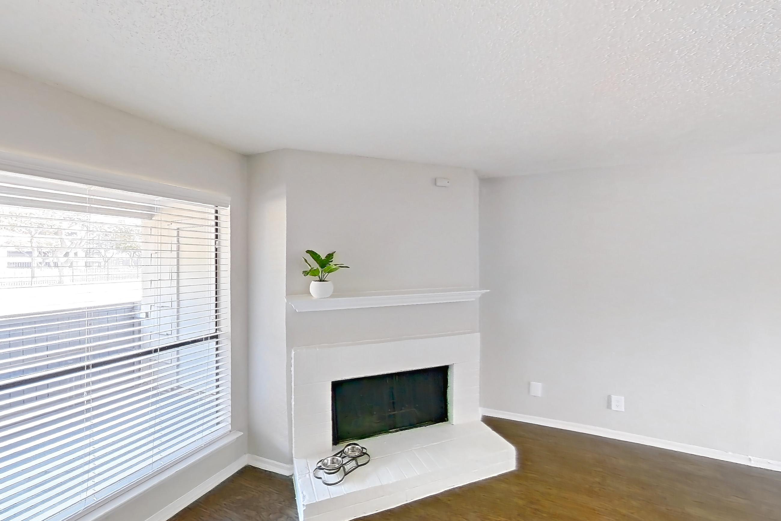 Living room with dark wood-finish flooring and fireplace, Apartment 0105 at Prestonwood Apartment Homes