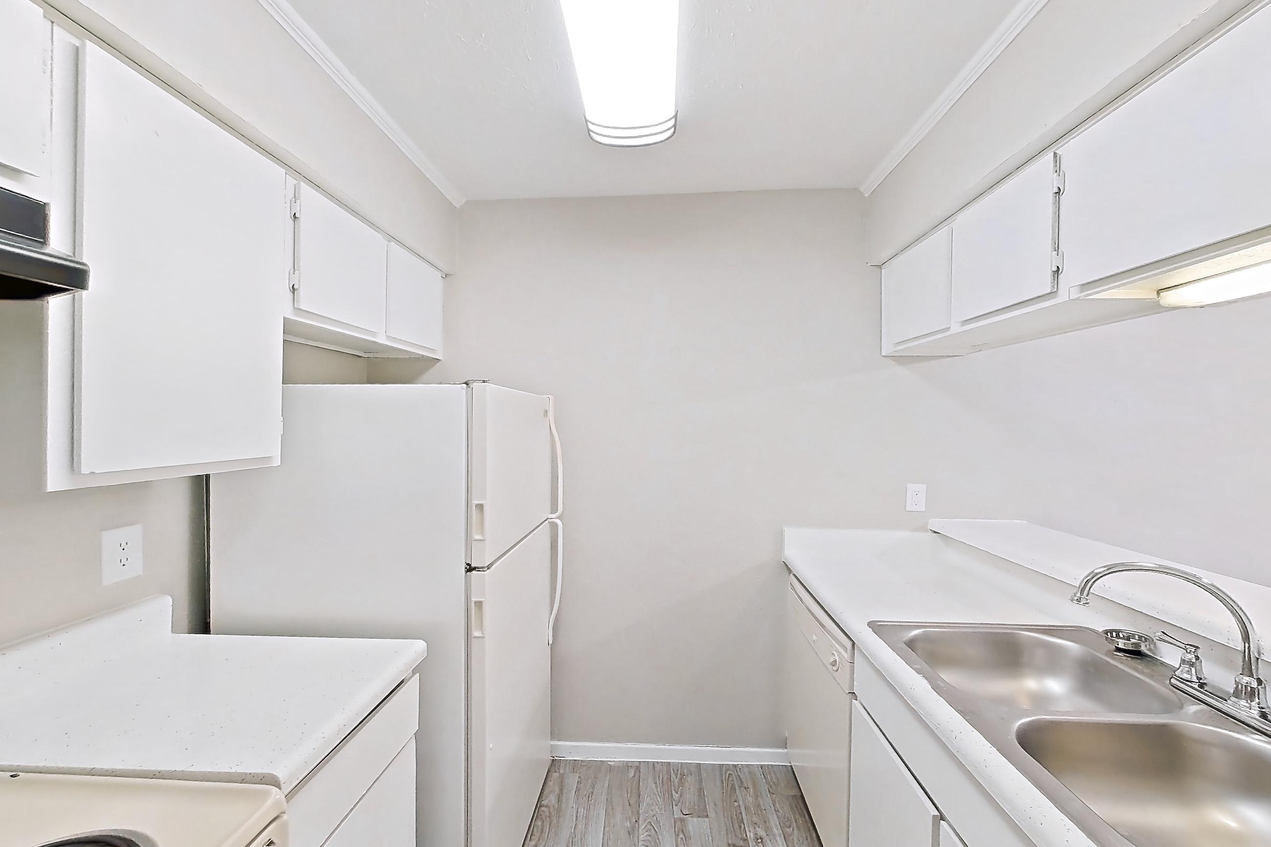 Kitchen with dishwasher, electric range, light countertops, light stone countertops, light wood-finish flooring, oven/range, range hood, refrigerator, and white appliances, Apartment 825 at Westgate
