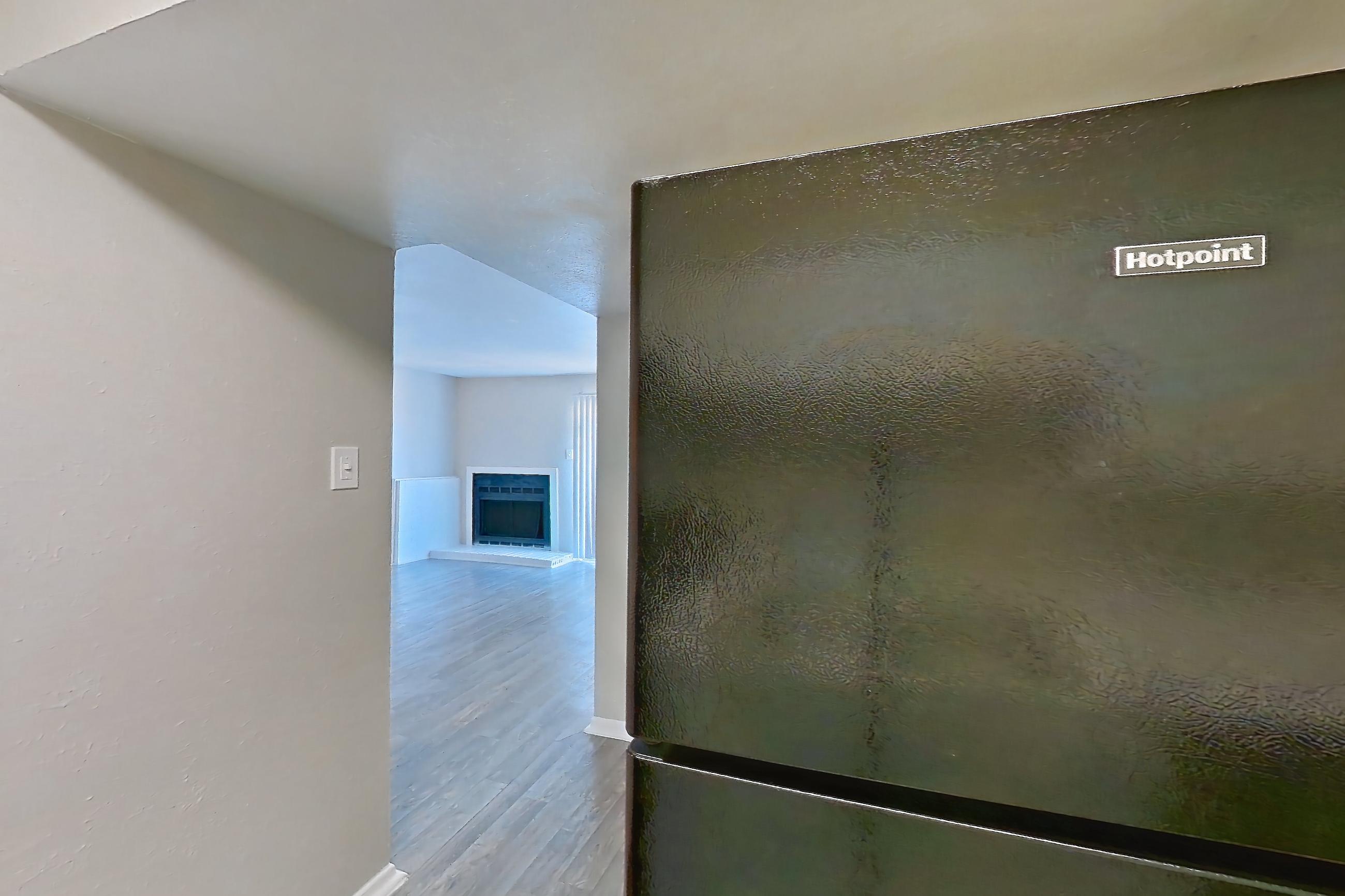 Kitchen with black appliances, dishwasher, electric range, light countertops, light stone countertops, light wood-finish flooring, oven/range, and range hood, Apartment 1322 at Westgate