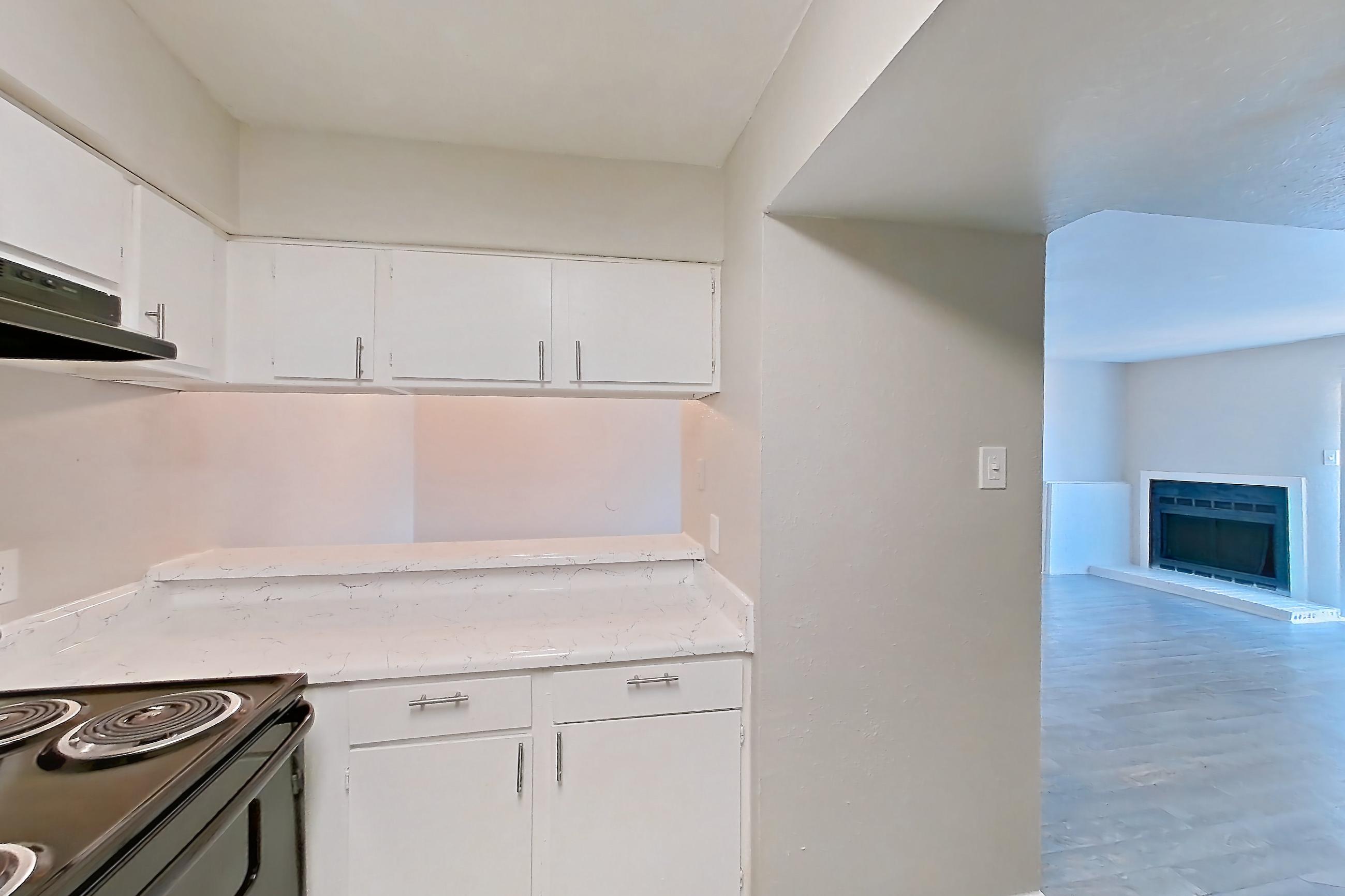 Kitchen with black appliances, dishwasher, electric range, light countertops, light stone countertops, light wood-finish flooring, oven/range, and range hood, Apartment 1322 at Westgate