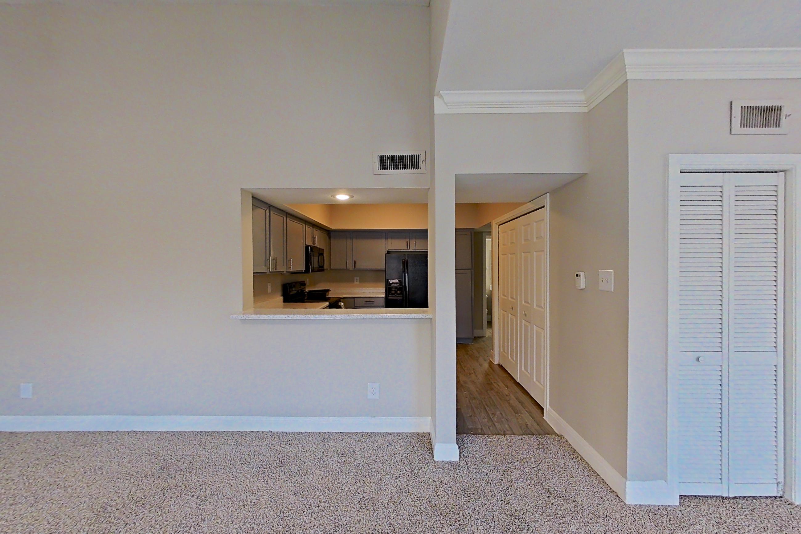 Living room with black appliances, light carpet, and refrigerator, Unit 1202 at Champions Park