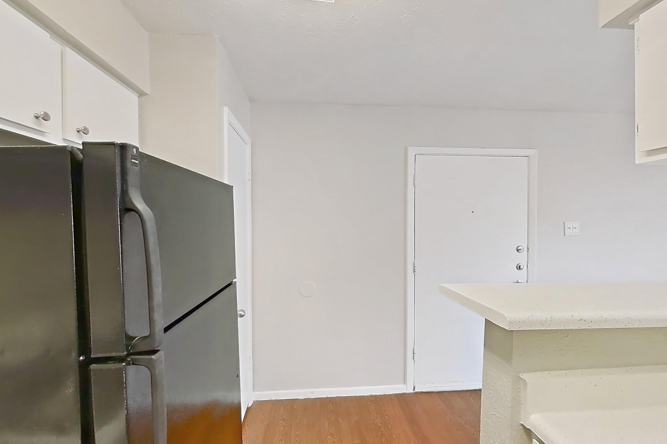 Kitchen with black appliances, dark wood-finish flooring, electric range, light countertops, light wood-finish flooring, oven/range, range hood, and refrigerator, Apartment 2024 at Westgate