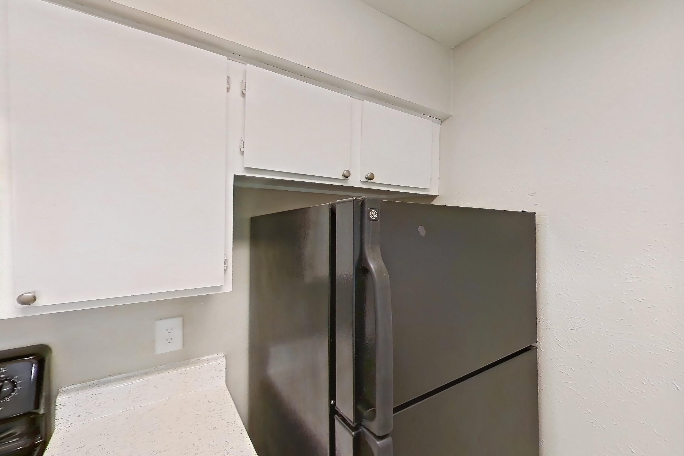 Kitchen with black appliances, dishwasher, electric range, light countertops, light stone countertops, light wood-finish flooring, oven/range, and refrigerator, Apartment 2121 at Westgate