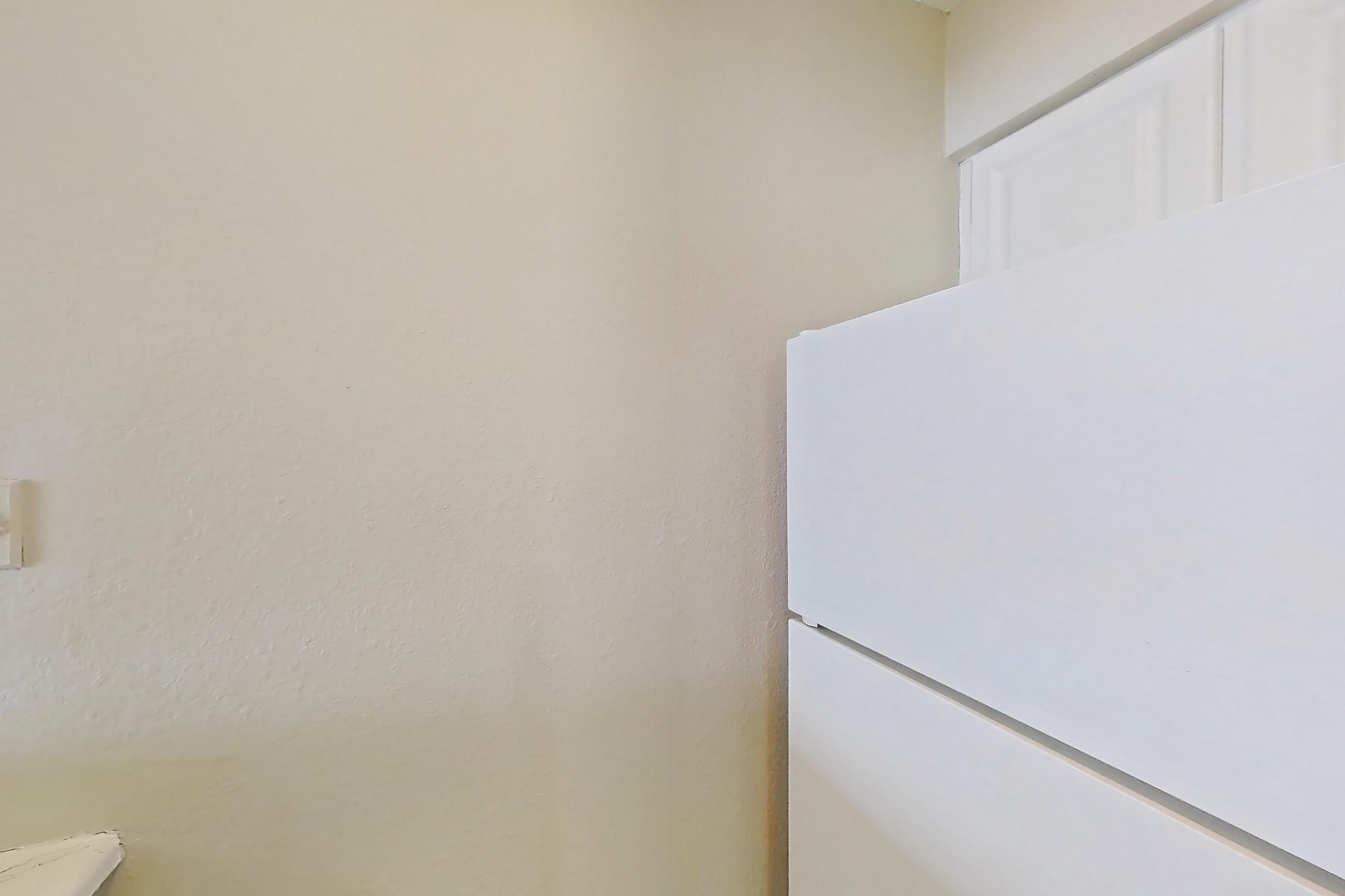 Kitchen with black appliances, electric range, light countertops, light stone countertops, light wood-finish flooring, microwave, oven/range, refrigerator, and white appliances, Apartment C-88 at Sunset Place