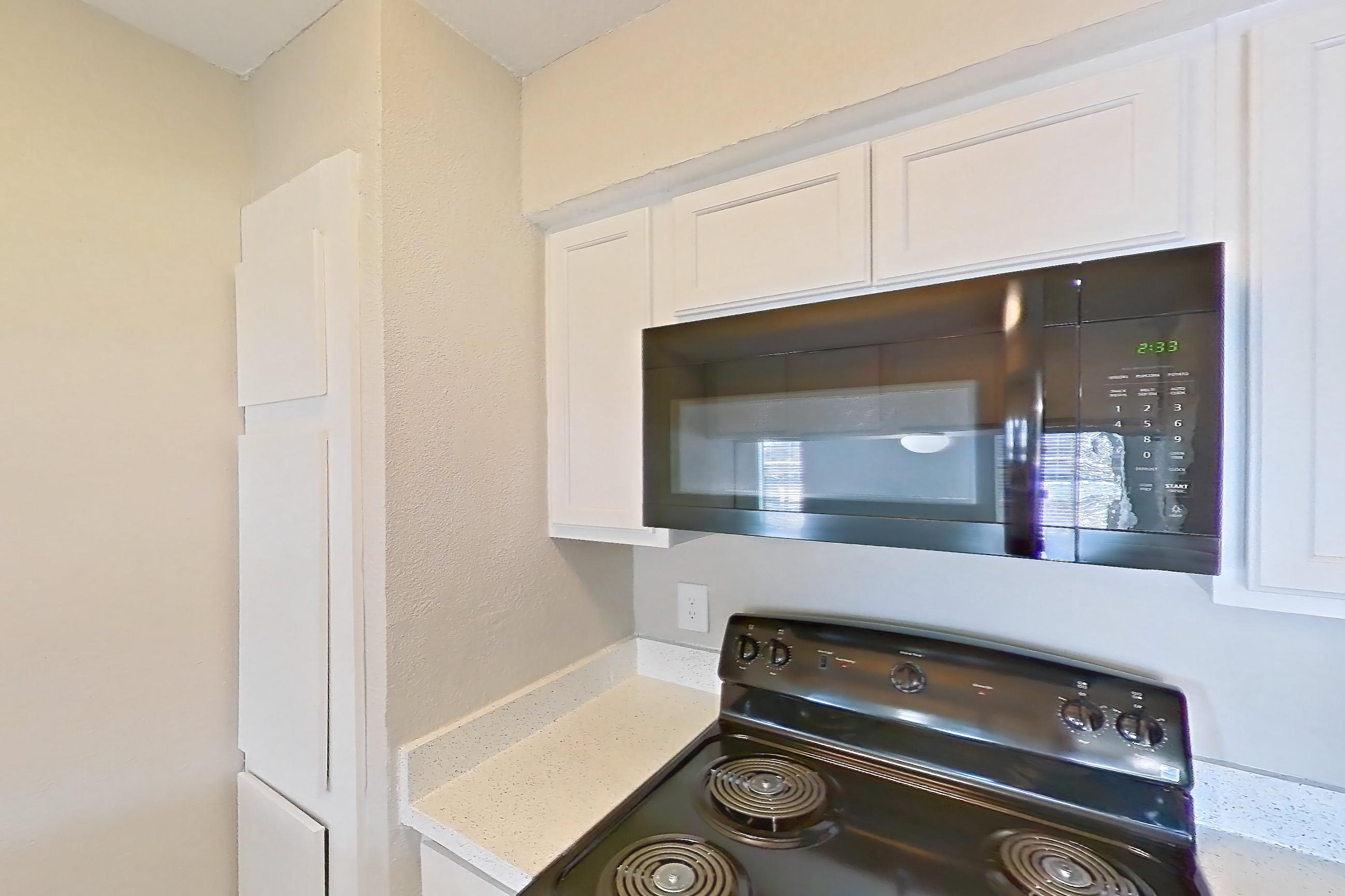 Kitchen with black appliances, dishwasher, electric range, light countertops, light stone countertops, light wood-finish flooring, oven/range, and refrigerator, Apartment 182 at Sedona Park