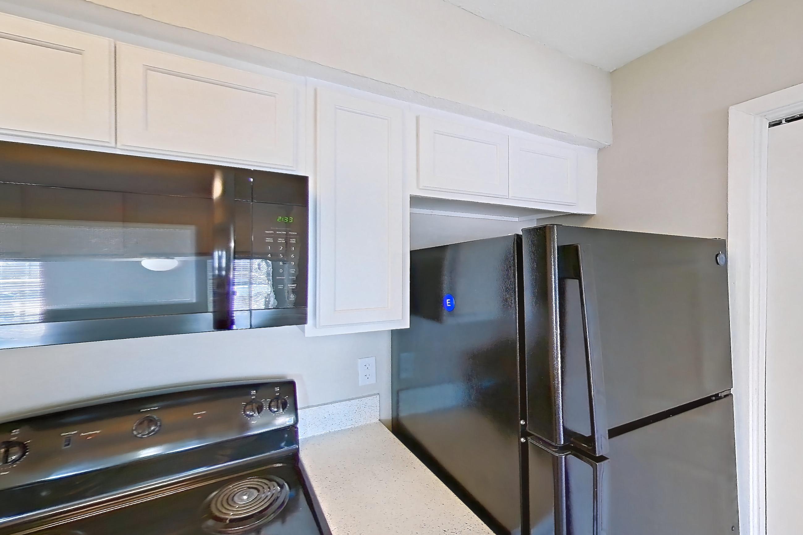 Kitchen with black appliances, dishwasher, electric range, light countertops, light stone countertops, light wood-finish flooring, oven/range, and refrigerator, Apartment 182 at Sedona Park