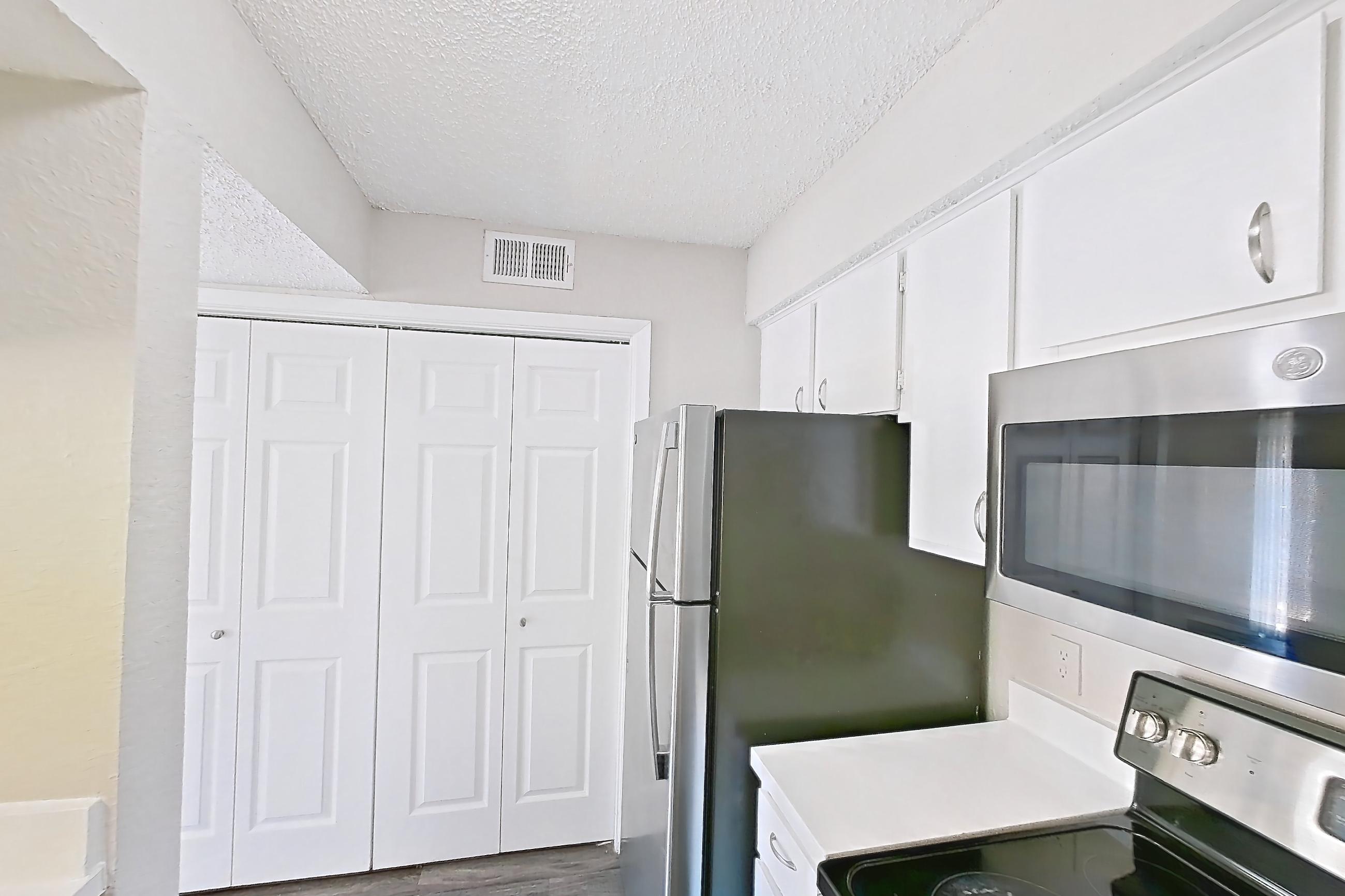 Kitchen with dark wood-finish flooring, dishwasher, electric range, light countertops, microwave, oven/range, refrigerator, and stainless steel appliances, Apartment 195 at Sedona Park