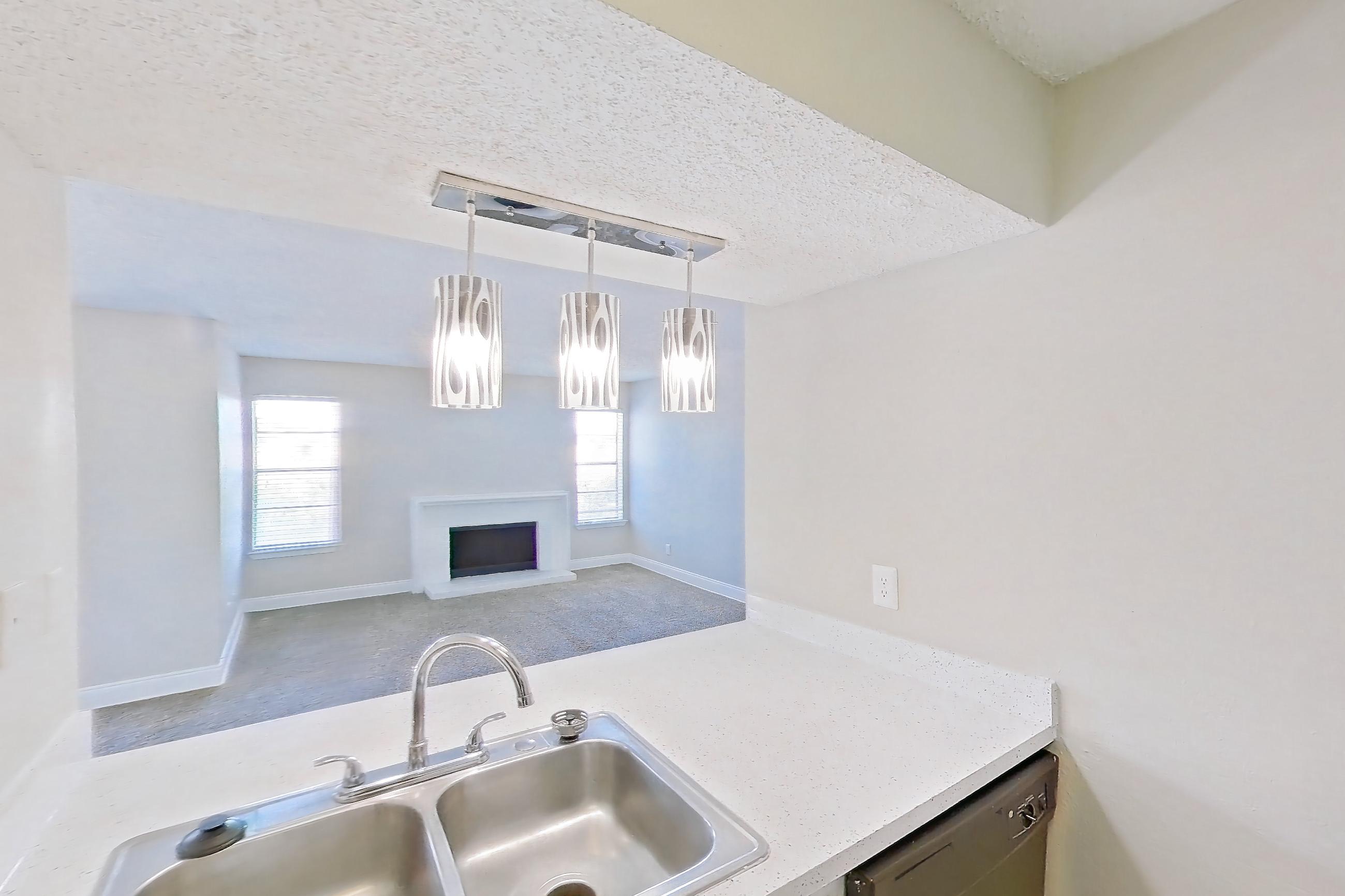 Kitchen with black appliances, dishwasher, electric range, fireplace, light countertops, light stone countertops, light wood-finish flooring, microwave, oven/range, refrigerator, stainless steel appliances, and wood-look tile flooring, Apartment 232 at Sedona Park