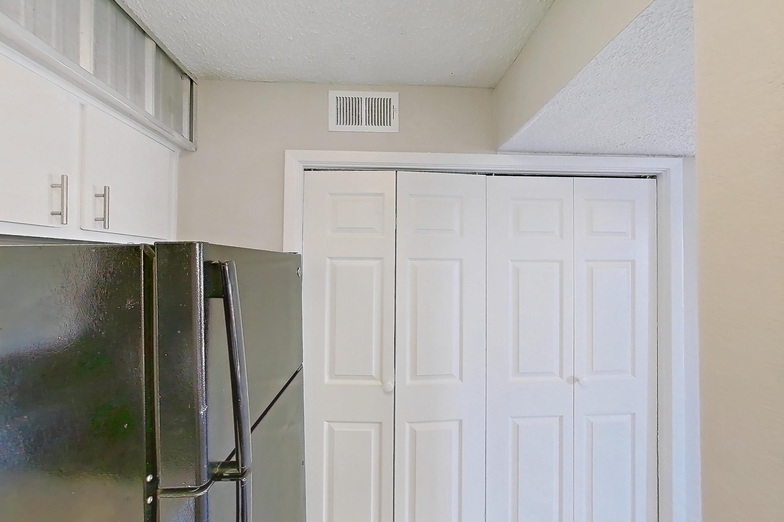 Kitchen with black appliances, dishwasher, electric range, fireplace, light countertops, light stone countertops, light wood-finish flooring, microwave, oven/range, refrigerator, stainless steel appliances, and wood-look tile flooring, Apartment 232 at Sedona Park