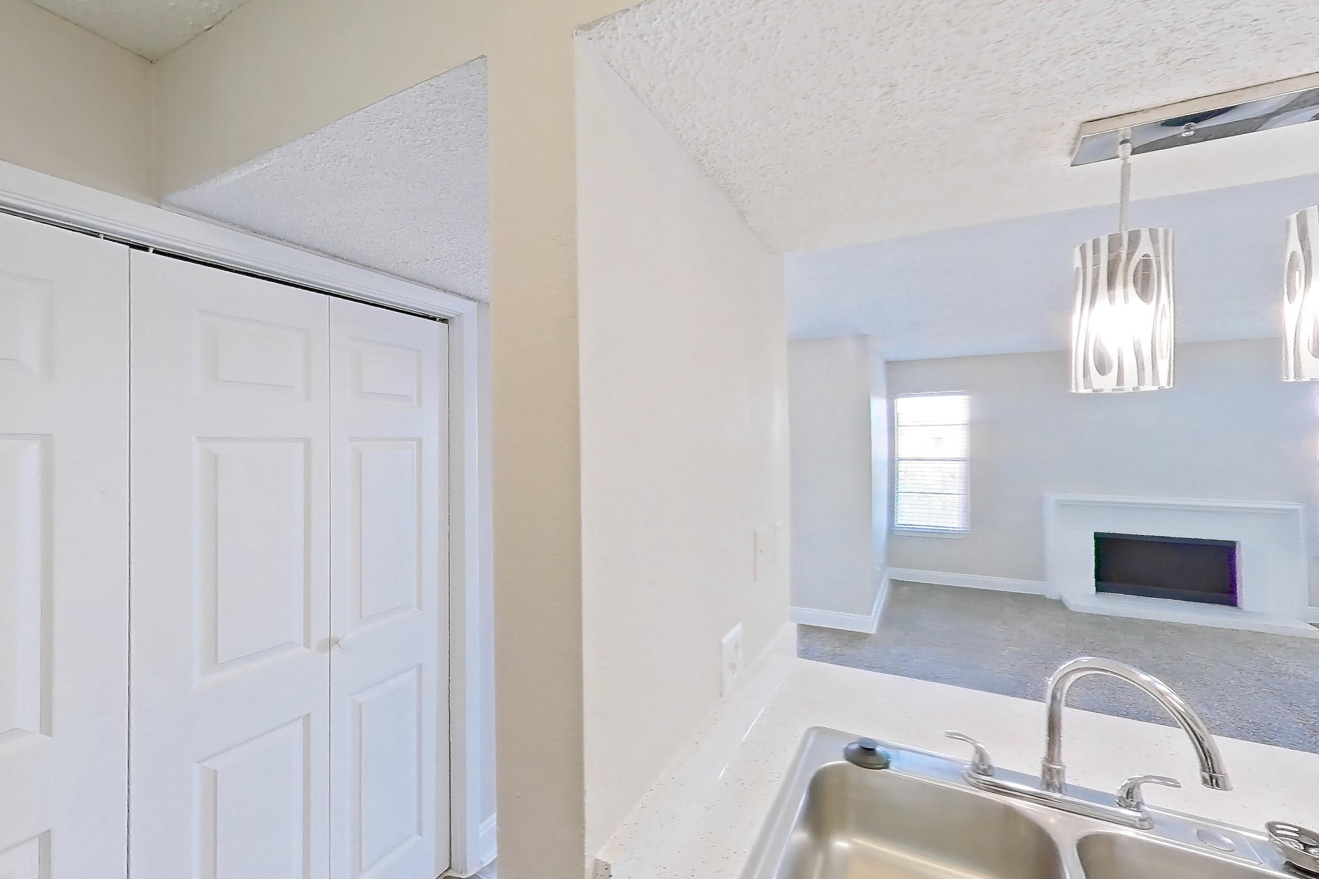 Kitchen with black appliances, dishwasher, electric range, fireplace, light countertops, light stone countertops, light wood-finish flooring, microwave, oven/range, refrigerator, stainless steel appliances, and wood-look tile flooring, Apartment 232 at Sedona Park