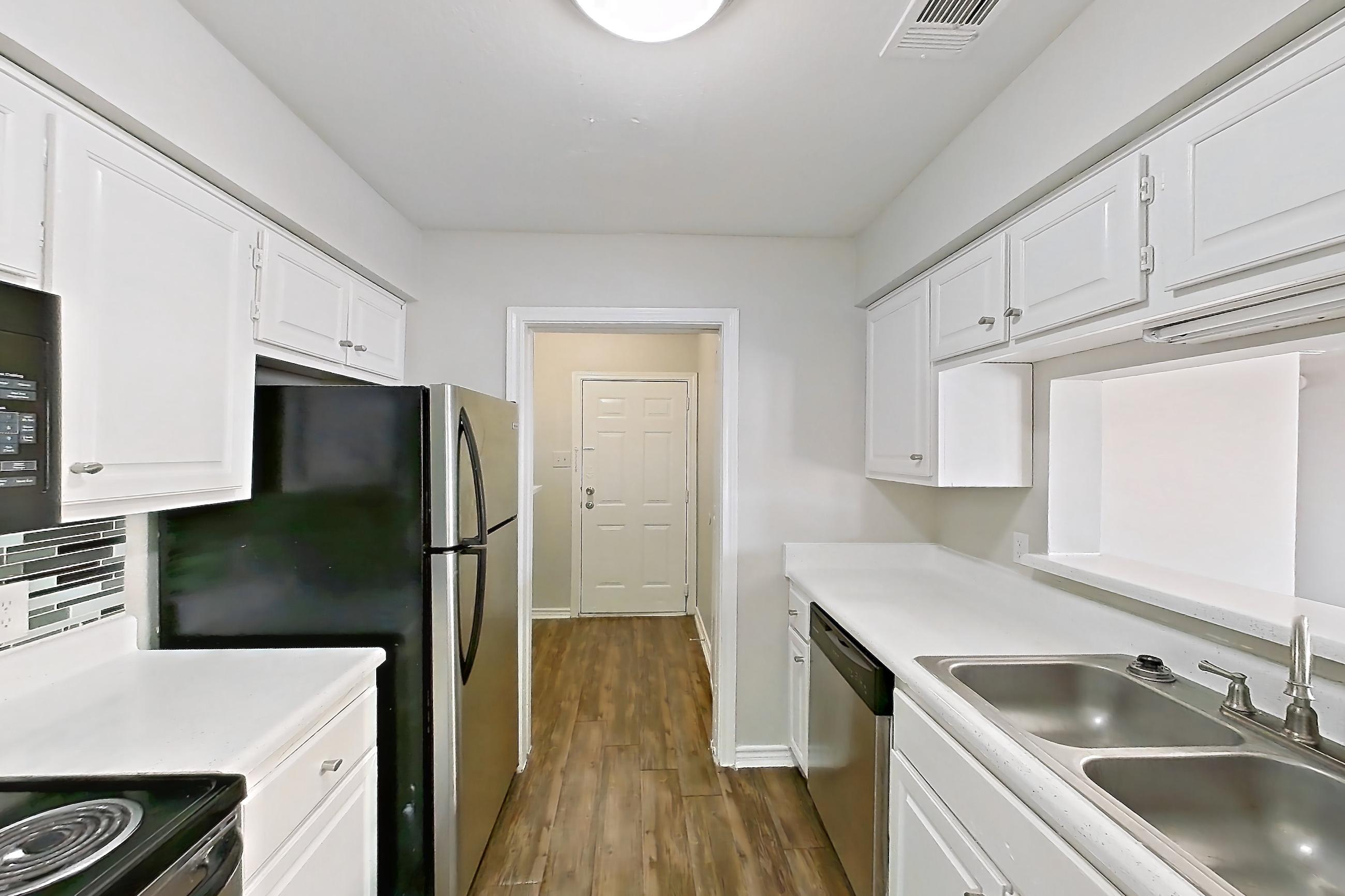 Kitchen with dark wood-finish flooring, dishwasher, electric range, light countertops, oven/range, refrigerator, and stainless steel appliances, Apartment 1211 at Arlington Hills