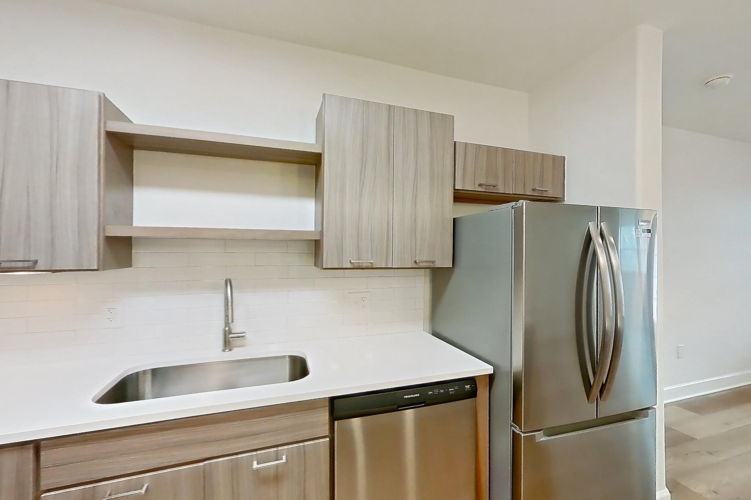 Kitchen with dishwasher, electric range, light countertops, light stone countertops, light wood-finish flooring, oven/range, refrigerator, stainless steel appliances, and water & ice dispenser, Apartment 206 at Talcott at Windermere