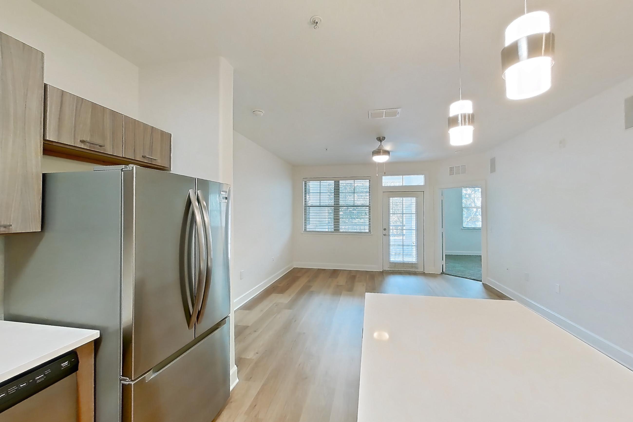 Kitchen with dishwasher, electric range, light countertops, light stone countertops, light wood-finish flooring, oven/range, refrigerator, stainless steel appliances, and water & ice dispenser, Apartment 206 at Talcott at Windermere