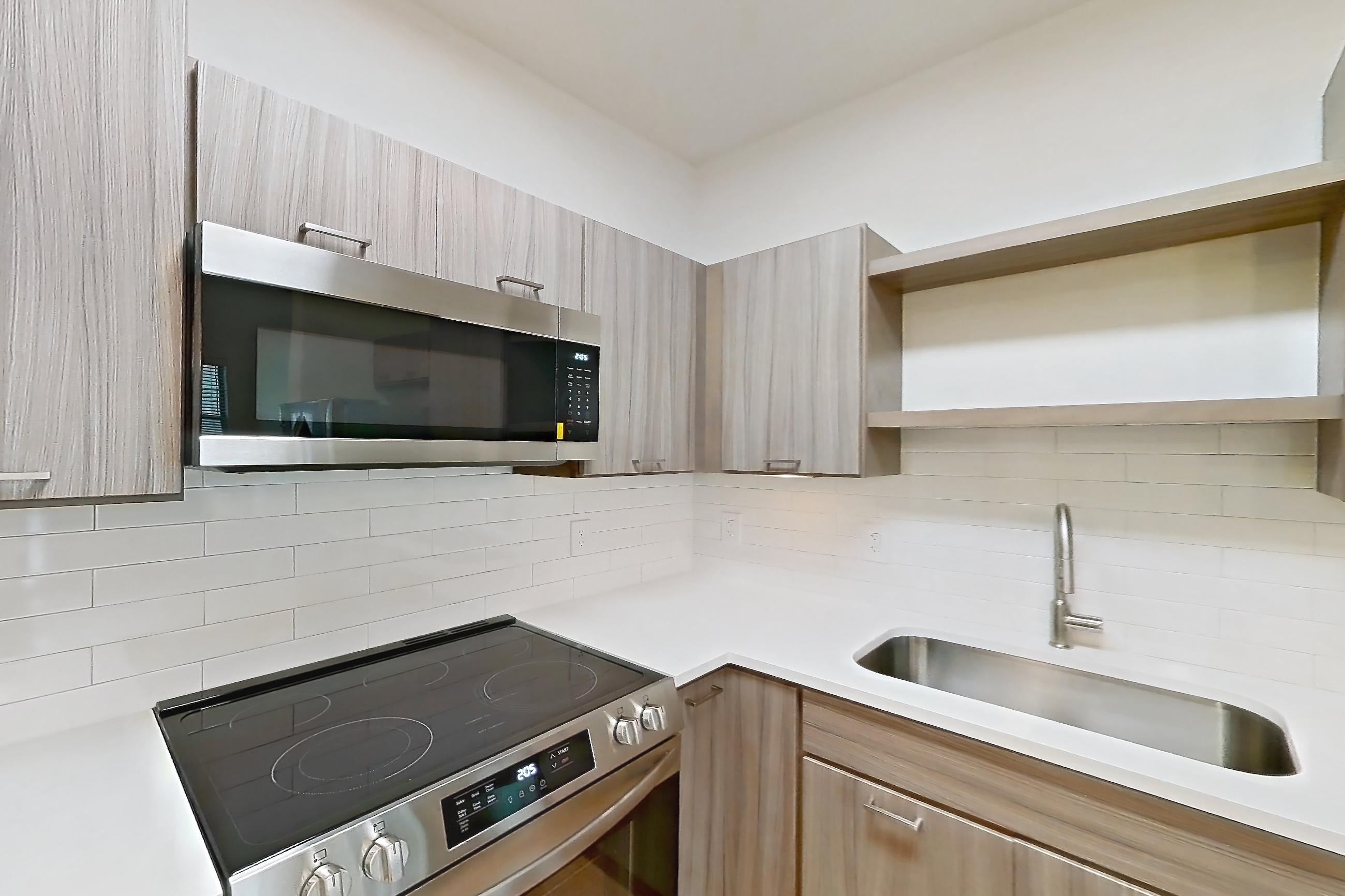 Kitchen with dishwasher, electric range, light countertops, light stone countertops, light wood-finish flooring, oven/range, refrigerator, stainless steel appliances, and water & ice dispenser, Apartment 206 at Talcott at Windermere